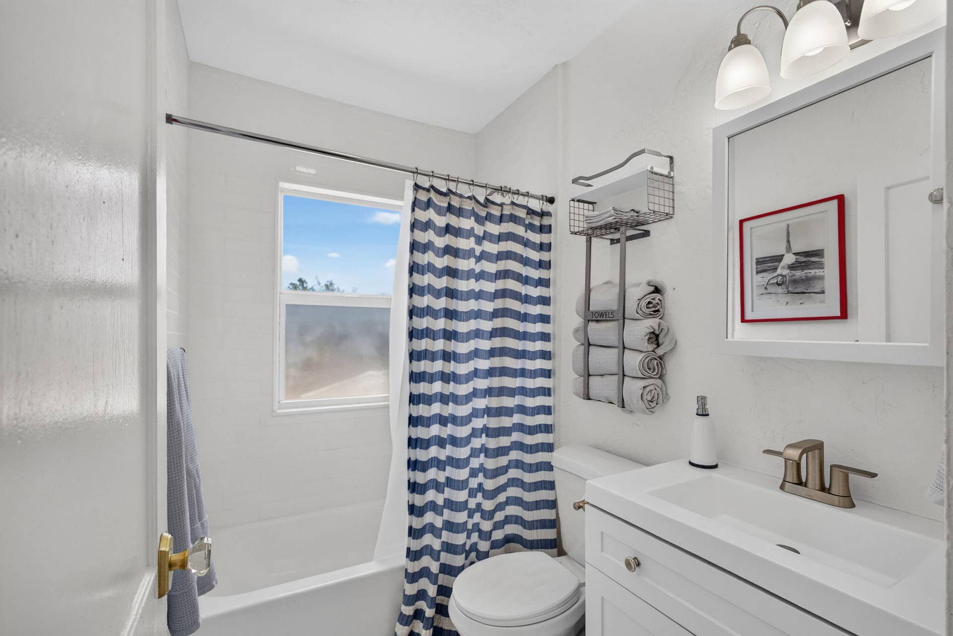 Bathroom featuring a white vanity with an integrated sink, brushed-metal faucet, wall-mounted medicine cabinet, triple-light vanity fixture, and a tub-shower combination