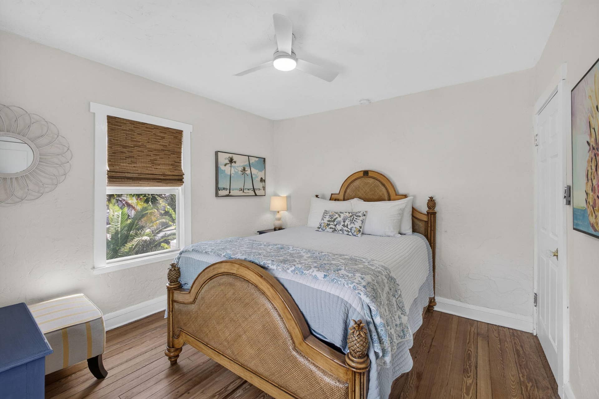 Wood-finish flooring, white ceiling fan with integrated lighting, and a single-pane window featuring a natural woven shade