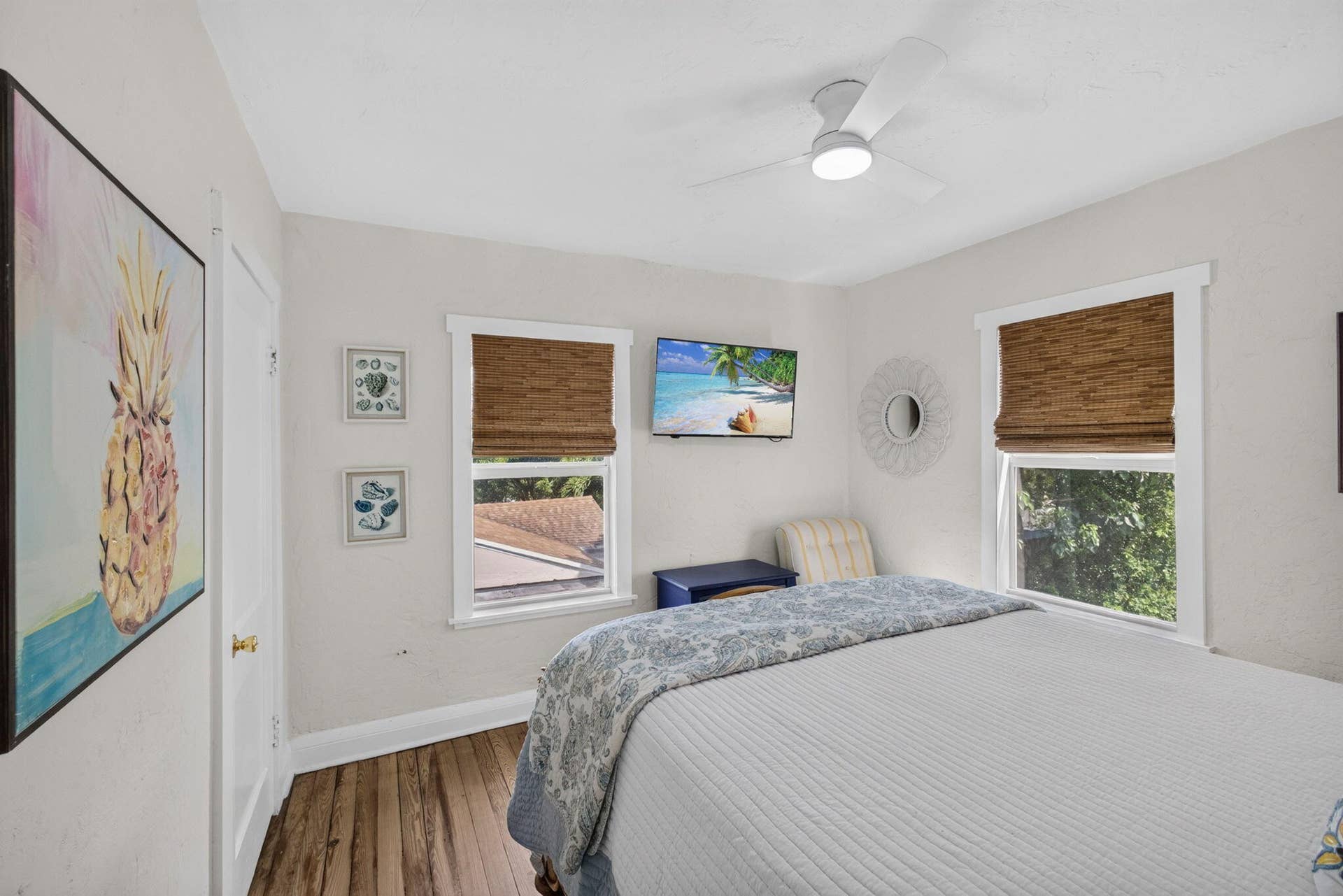Interior space featuring wood-finish flooring, two windows with white trim, and a modern ceiling fan with integrated lighting