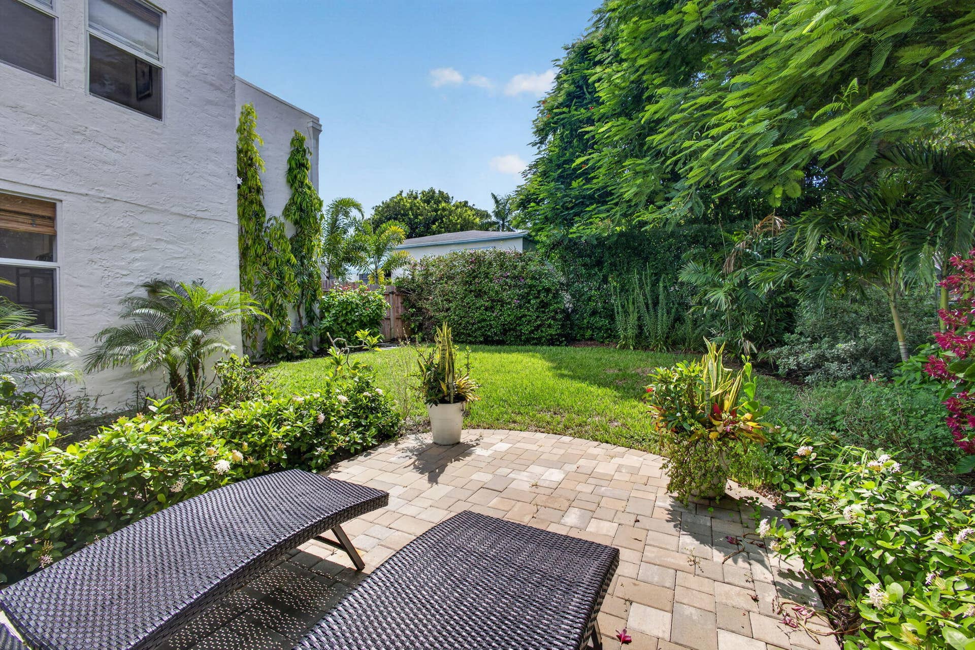 Backyard featuring a paved stone patio, manicured lawn, and established perimeter landscaping