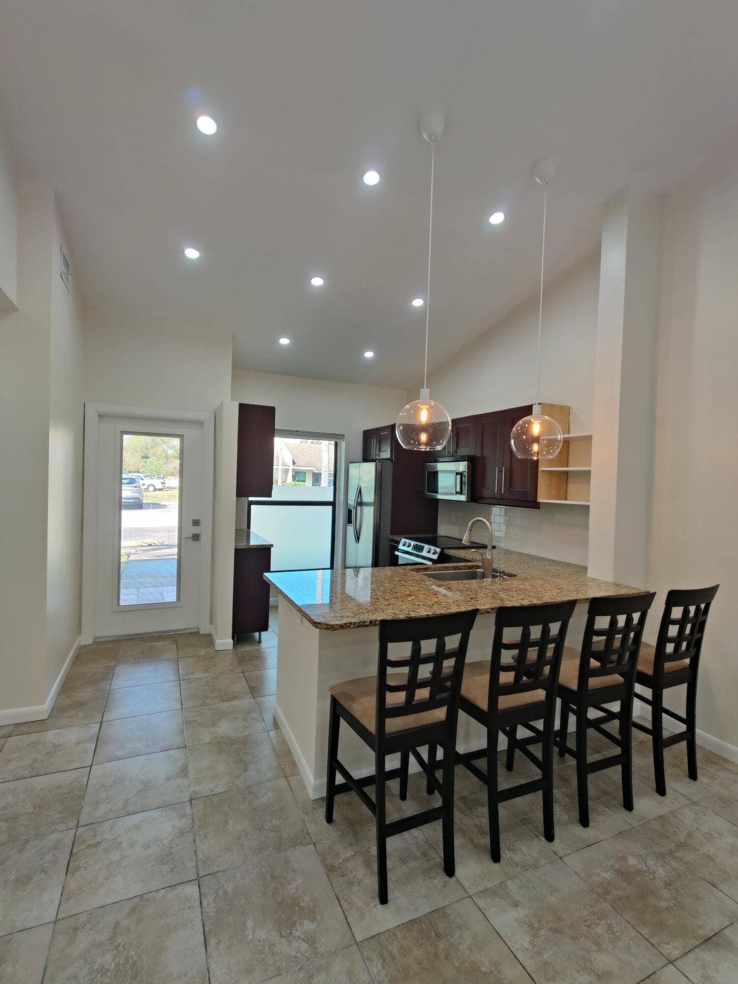 2700 S OAKLAND FOREST Drive, #603, Oakland Park, FL 33309 Kitchen featuring a stone-topped island, dark-toned cabinetry, recessed lighting, dual glass pendant lights, and tile flooring
