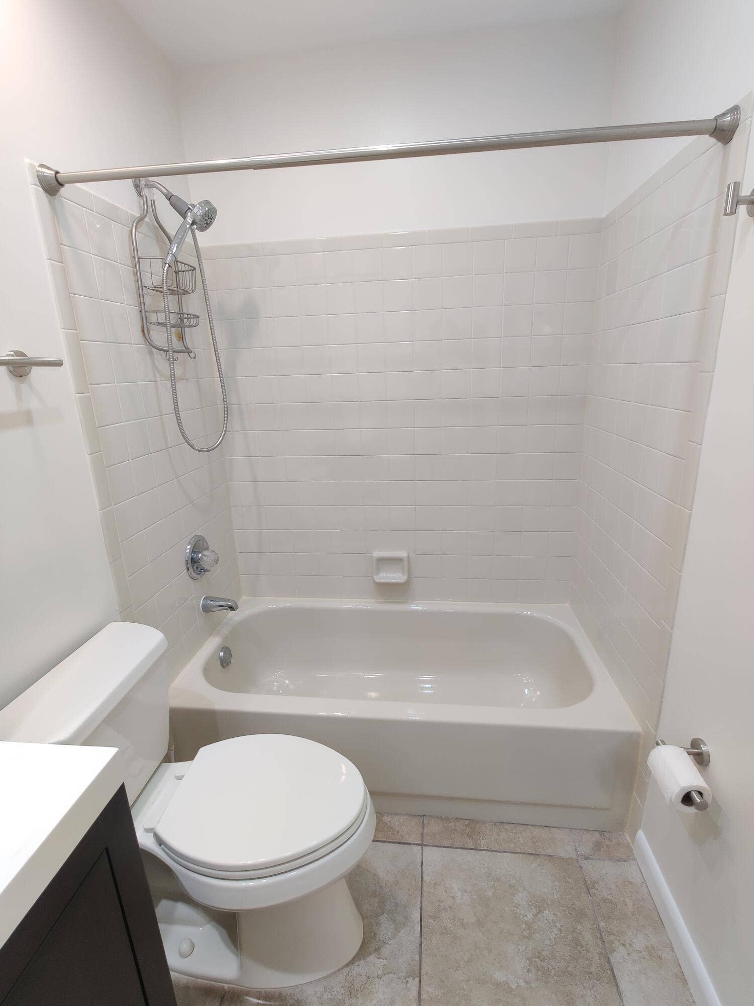 2700 S OAKLAND FOREST Drive, #603, Oakland Park, FL 33309 Bathtub and shower combination featuring light-toned wall tile, a handheld showerhead, a neutral vanity, and stone-finish flooring