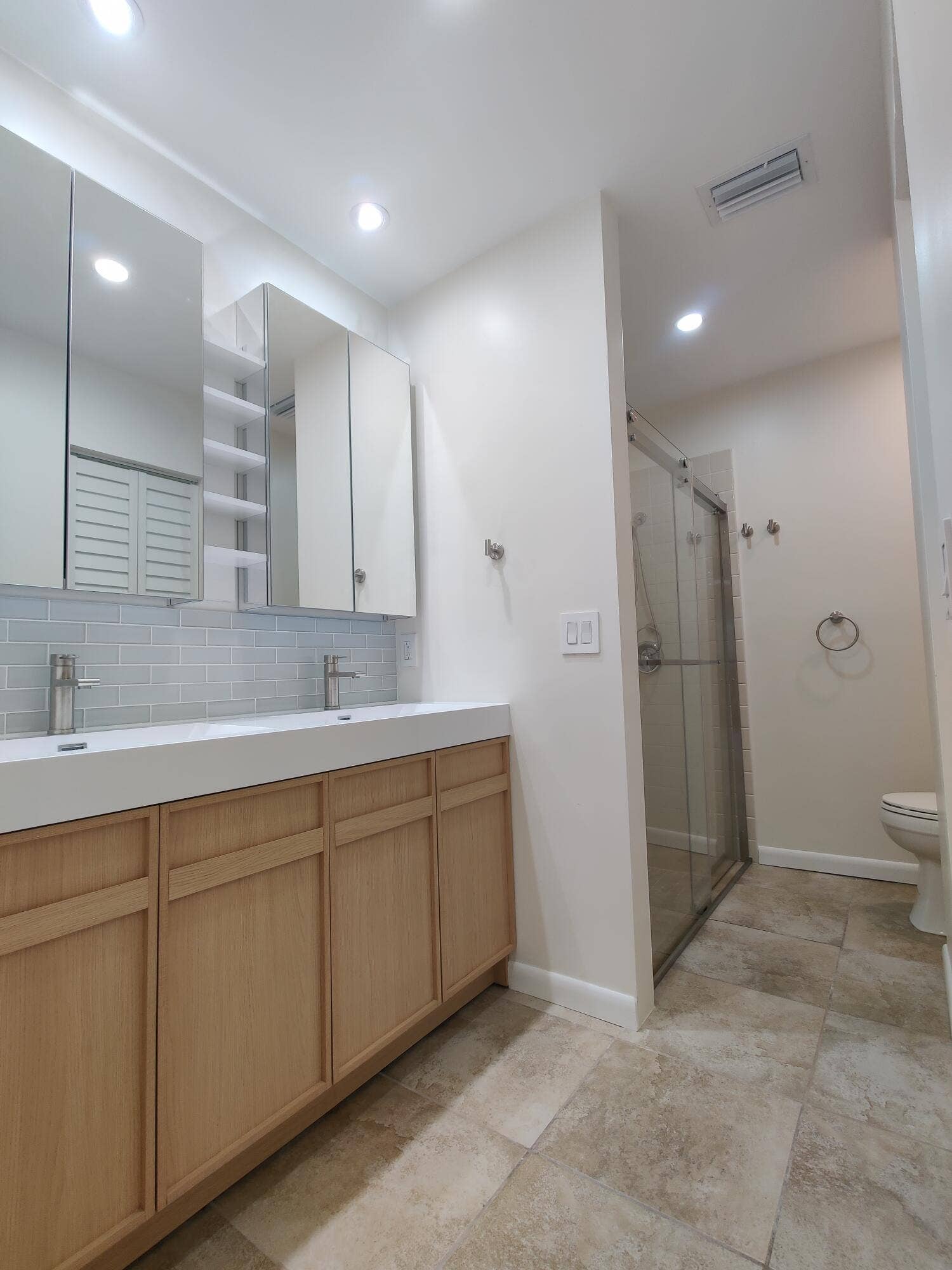 2700 S OAKLAND FOREST Drive, #603, Oakland Park, FL 33309 Dual-sink vanity with light wood cabinetry, integrated white countertops, recessed lighting, and a glass-enclosed shower with tile flooring