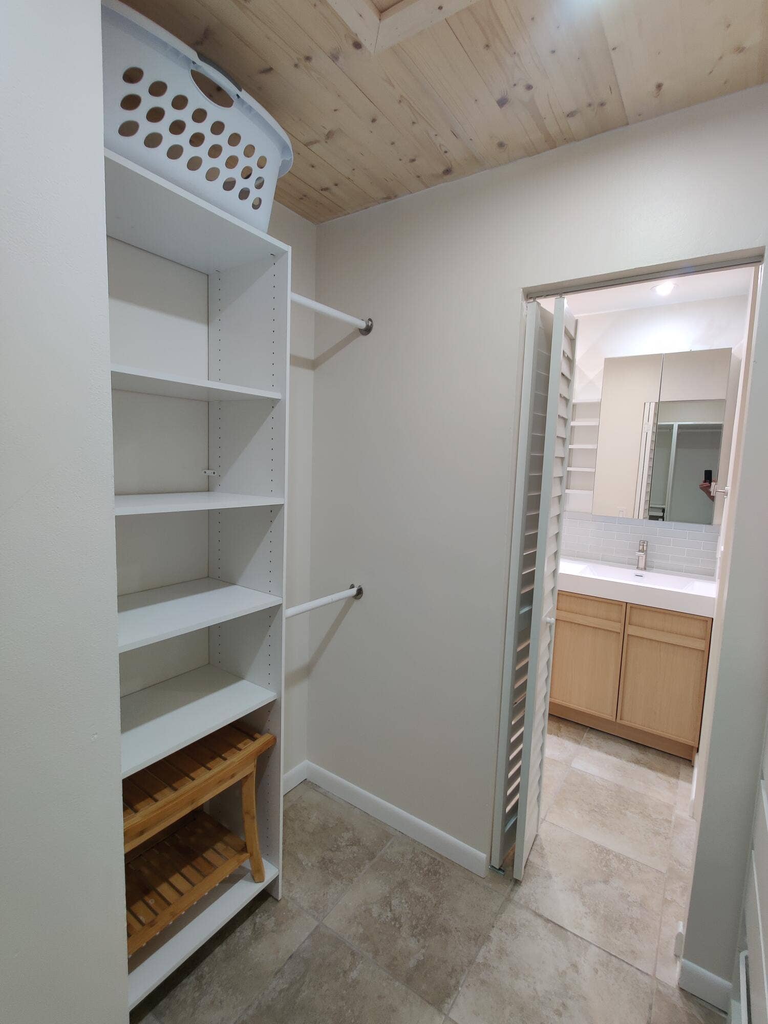 2700 S OAKLAND FOREST Drive, #603, Oakland Park, FL 33309 Storage closet featuring white built-in shelving, dual hanging rods, and natural wood-tone ceiling planks, with tile flooring