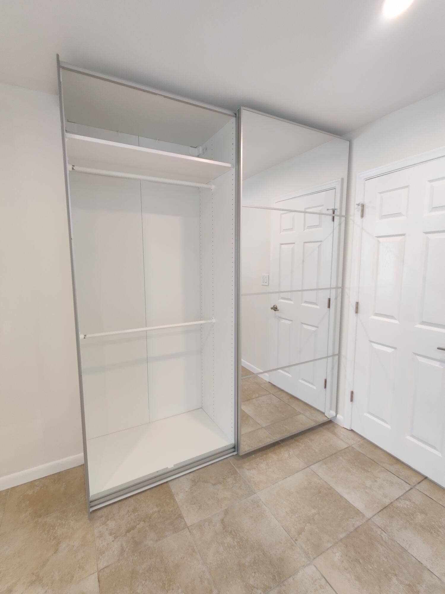 2700 S OAKLAND FOREST Drive, #603, Oakland Park, FL 33309 Sliding closet system featuring mirrored panels, integrated shelving, and horizontal hanging rods, complemented by tile flooring