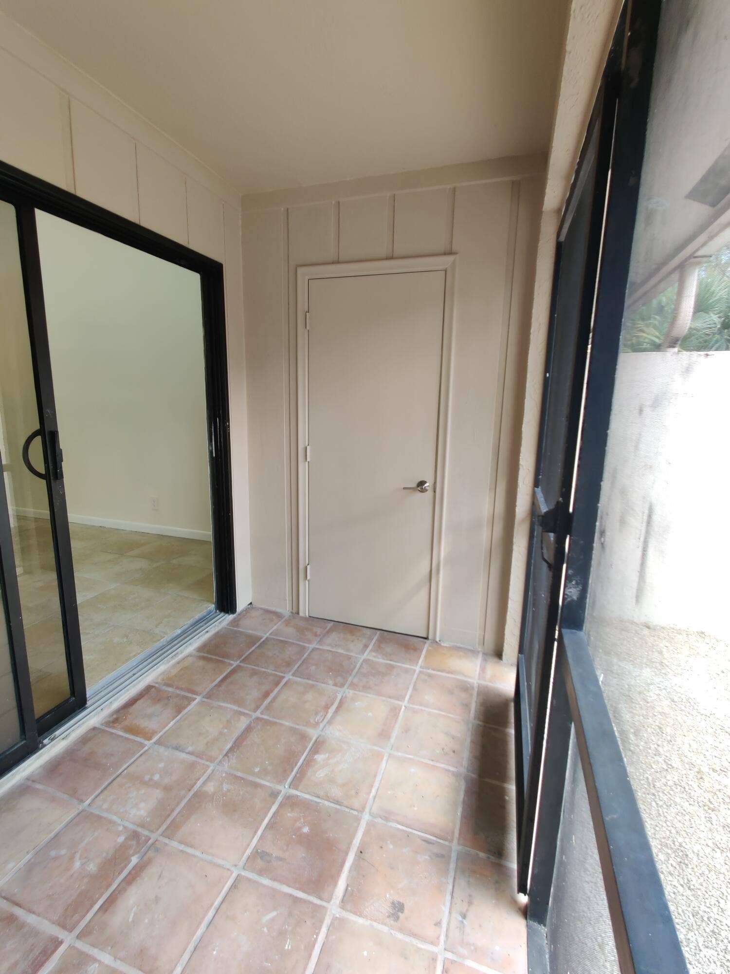 2700 S OAKLAND FOREST Drive, #603, Oakland Park, FL 33309 Enclosed porch featuring ceramic tile flooring, vertical wood-paneled walls, a single-panel interior door, and black-framed sliding glass doors