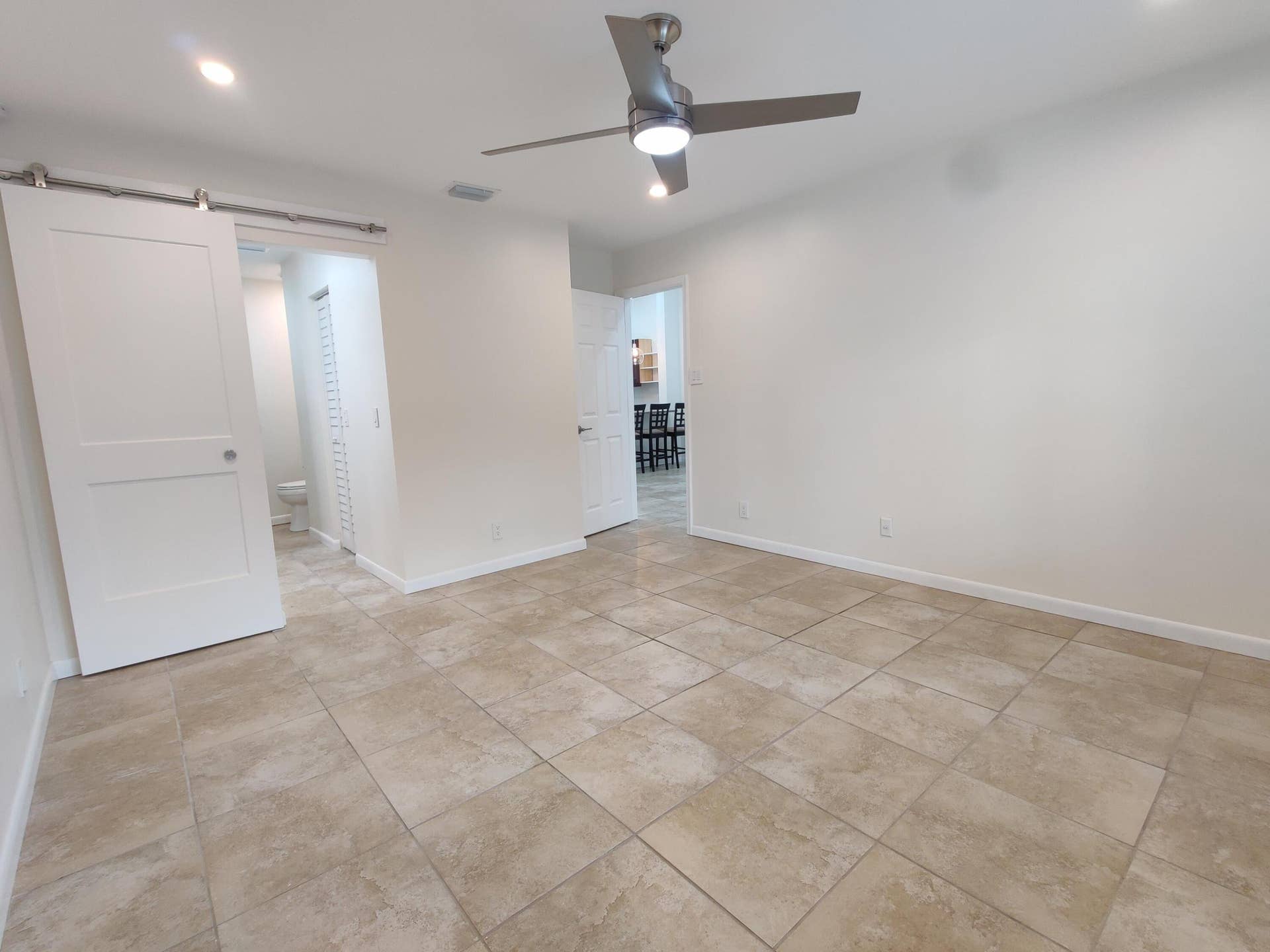 2700 S OAKLAND FOREST Drive, #603, Oakland Park, FL 33309 Interior space featuring large-format ceramic tile flooring, a brushed-nickel ceiling fan with integrated lighting, recessed ceiling lights, and a sliding door with exposed stainless steel hardware