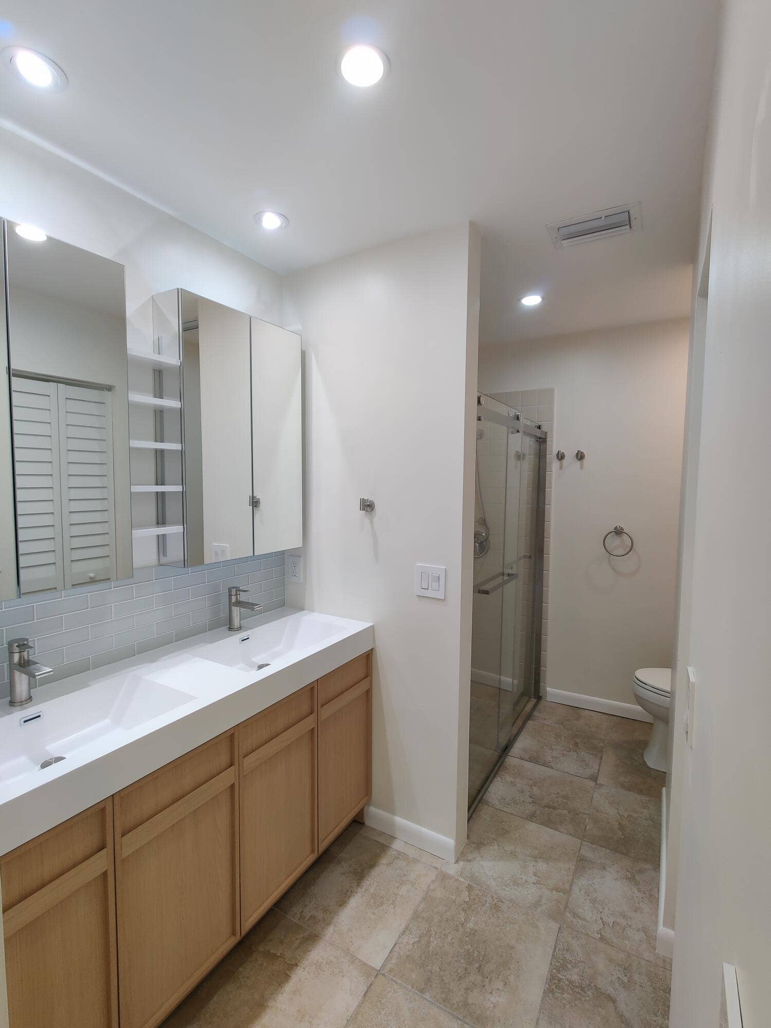 2700 S OAKLAND FOREST Drive, #603, Oakland Park, FL 33309 Double vanity with integrated sinks, wood-finish cabinetry, mirrored medicine cabinets, tiled flooring, and a glass-enclosed shower
