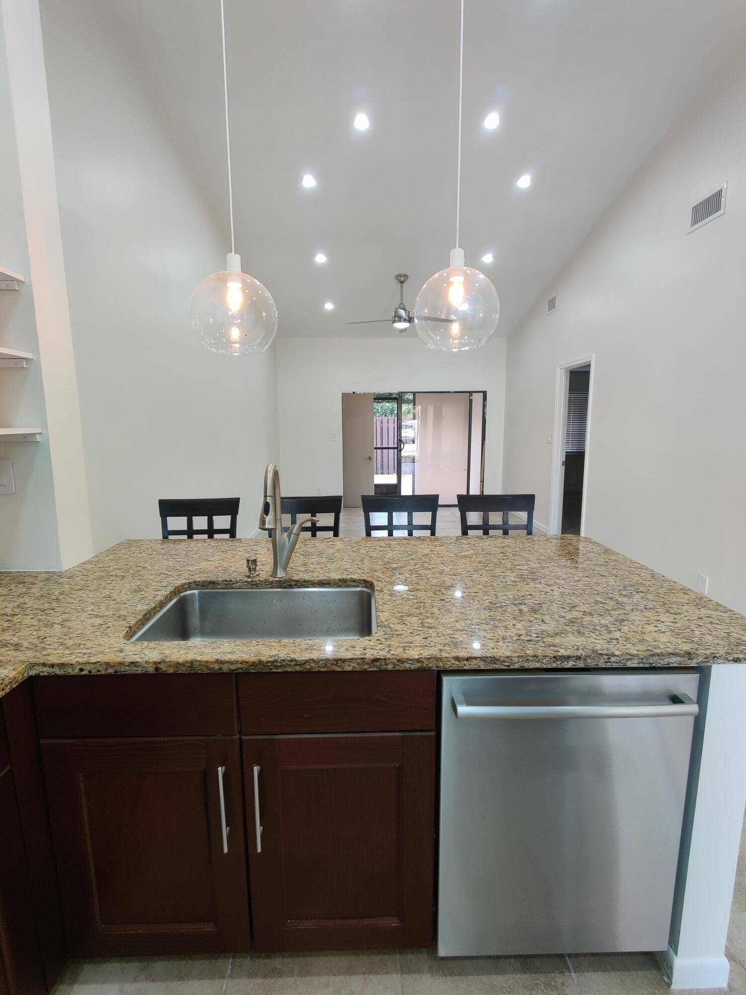 2700 S OAKLAND FOREST Drive, #603, Oakland Park, FL 33309 Kitchen island featuring a stone-look countertop, stainless steel undermount sink with a gooseneck faucet, dark wood-finish cabinetry, stainless steel dishwasher, and dual glass globe pendant lights