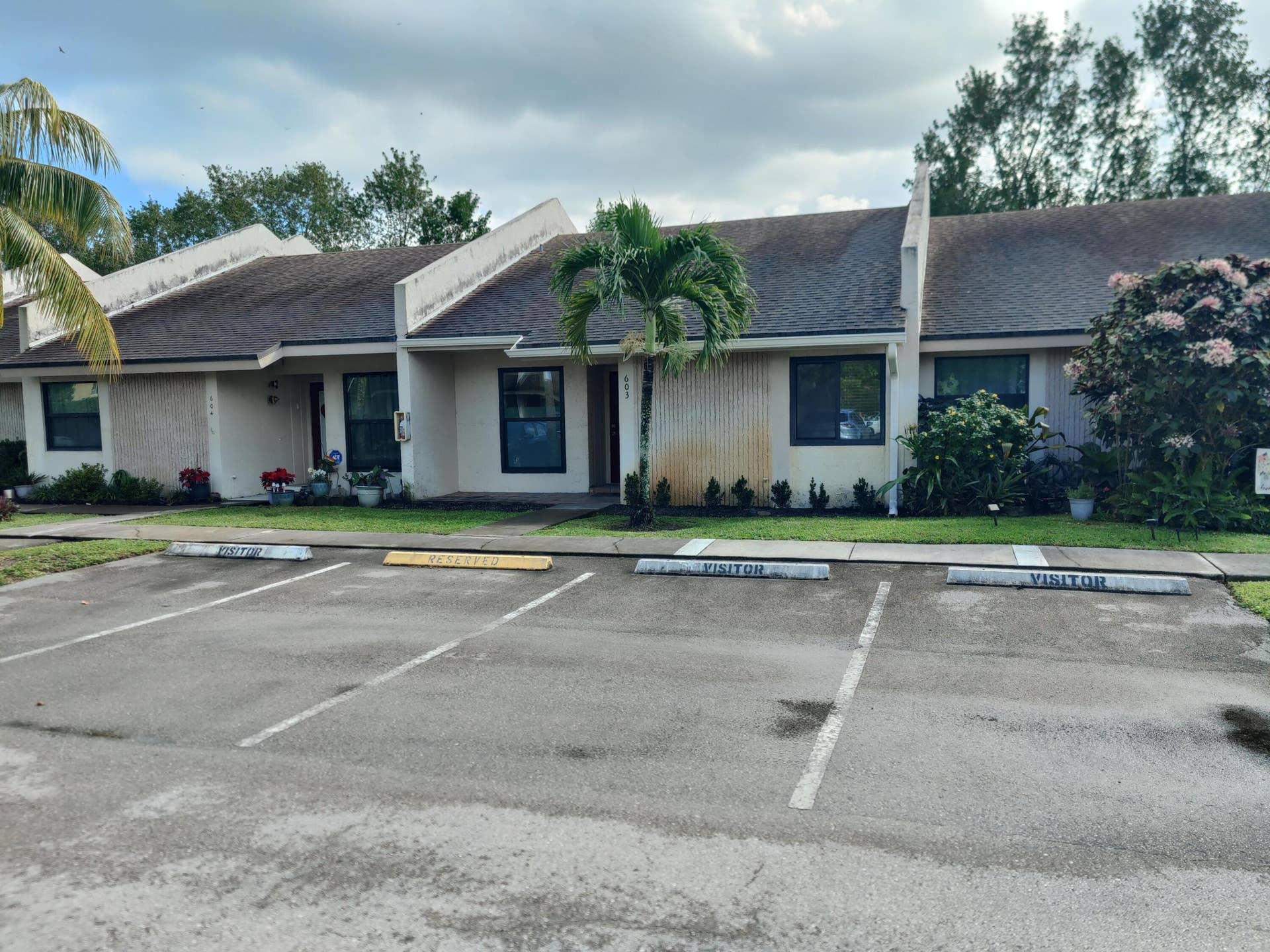 2700 S OAKLAND FOREST Drive, #603, Oakland Park, FL 33309 Single-story exterior featuring light-colored stucco siding, asphalt shingle roofing, and dedicated parking spaces