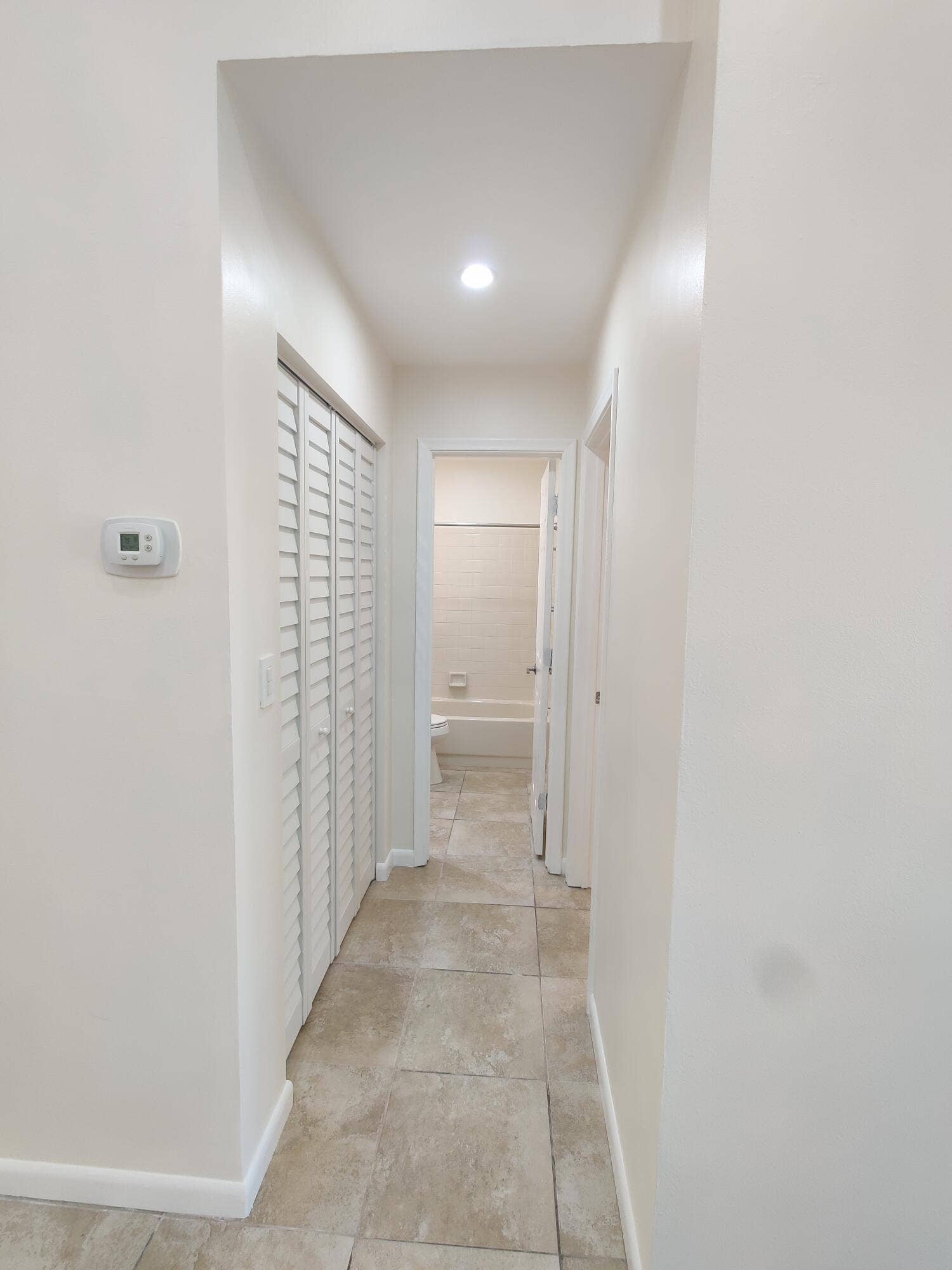 2700 S OAKLAND FOREST Drive, #603, Oakland Park, FL 33309 Hallway featuring large-format ceramic tile flooring, recessed ceiling lighting, and floor-to-ceiling louvered bi-fold closet doors