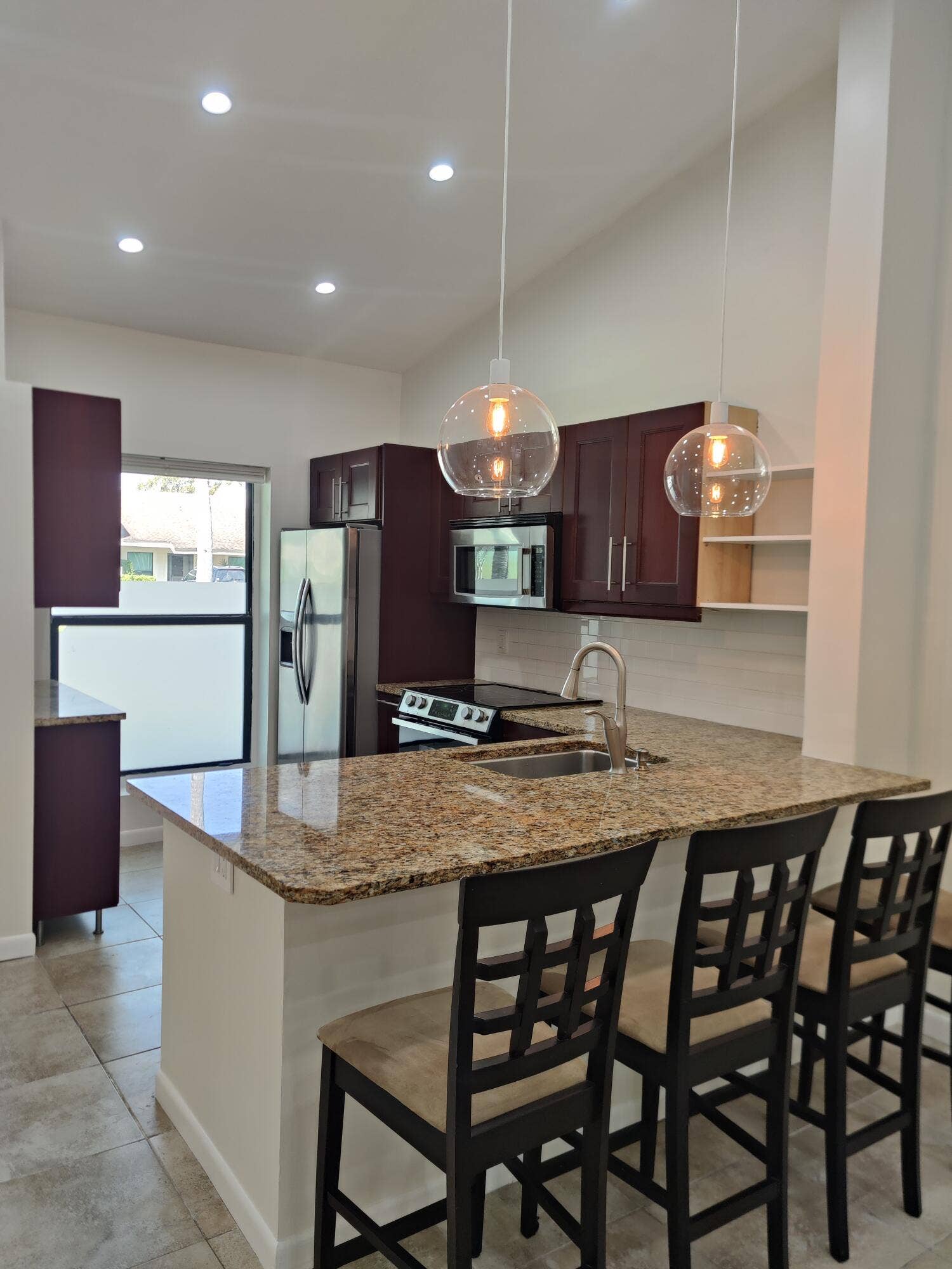 2700 S OAKLAND FOREST Drive, #603, Oakland Park, FL 33309 Kitchen featuring dark wood cabinetry, stone-surface countertops, stainless steel appliances, dual glass globe pendant lights, and tile flooring