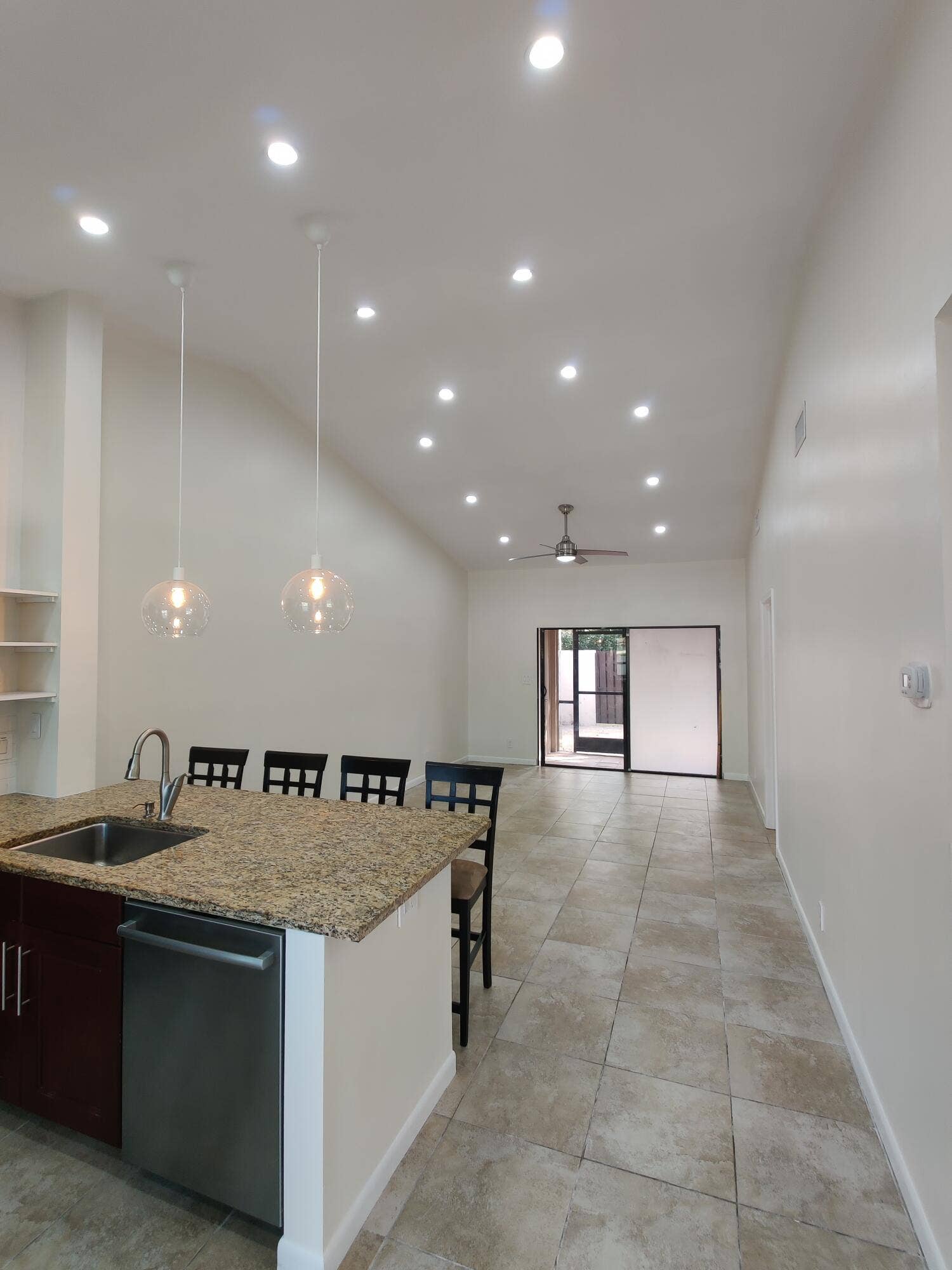 2700 S OAKLAND FOREST Drive, #603, Oakland Park, FL 33309 Open-concept interior featuring vaulted ceilings, recessed lighting, tile flooring, a kitchen island with a stone countertop, and two glass pendant lights