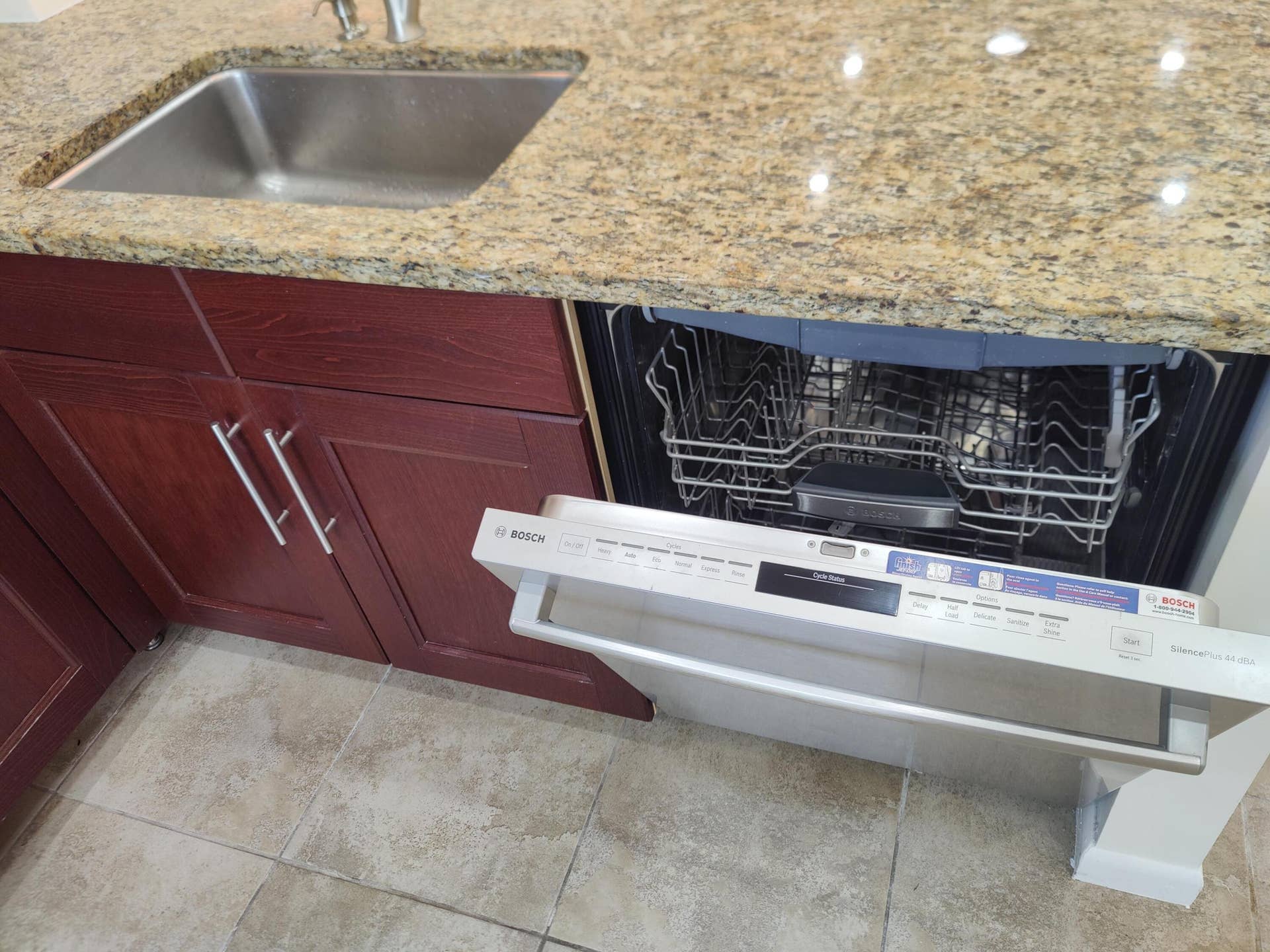 2700 S OAKLAND FOREST Drive, #603, Oakland Park, FL 33309 Stone countertop with an integrated undermount sink, cherry-finish wood cabinetry, and stainless steel Bosch dishwasher