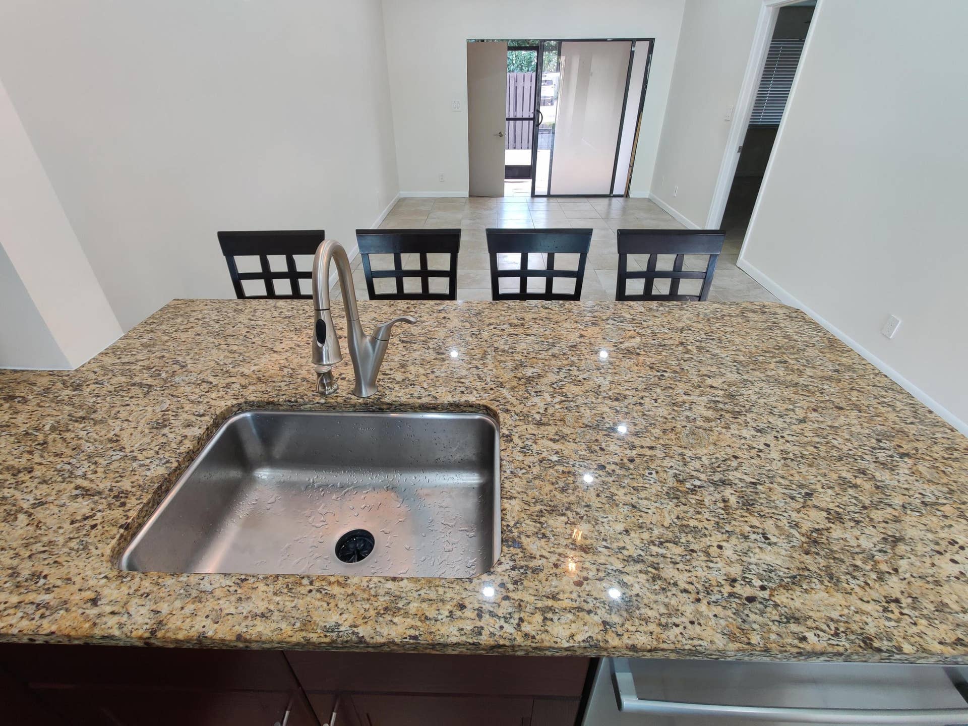 2700 S OAKLAND FOREST Drive, #603, Oakland Park, FL 33309 Kitchen island featuring a stone-look countertop, stainless steel undermount sink, and high-arc pull-down faucet