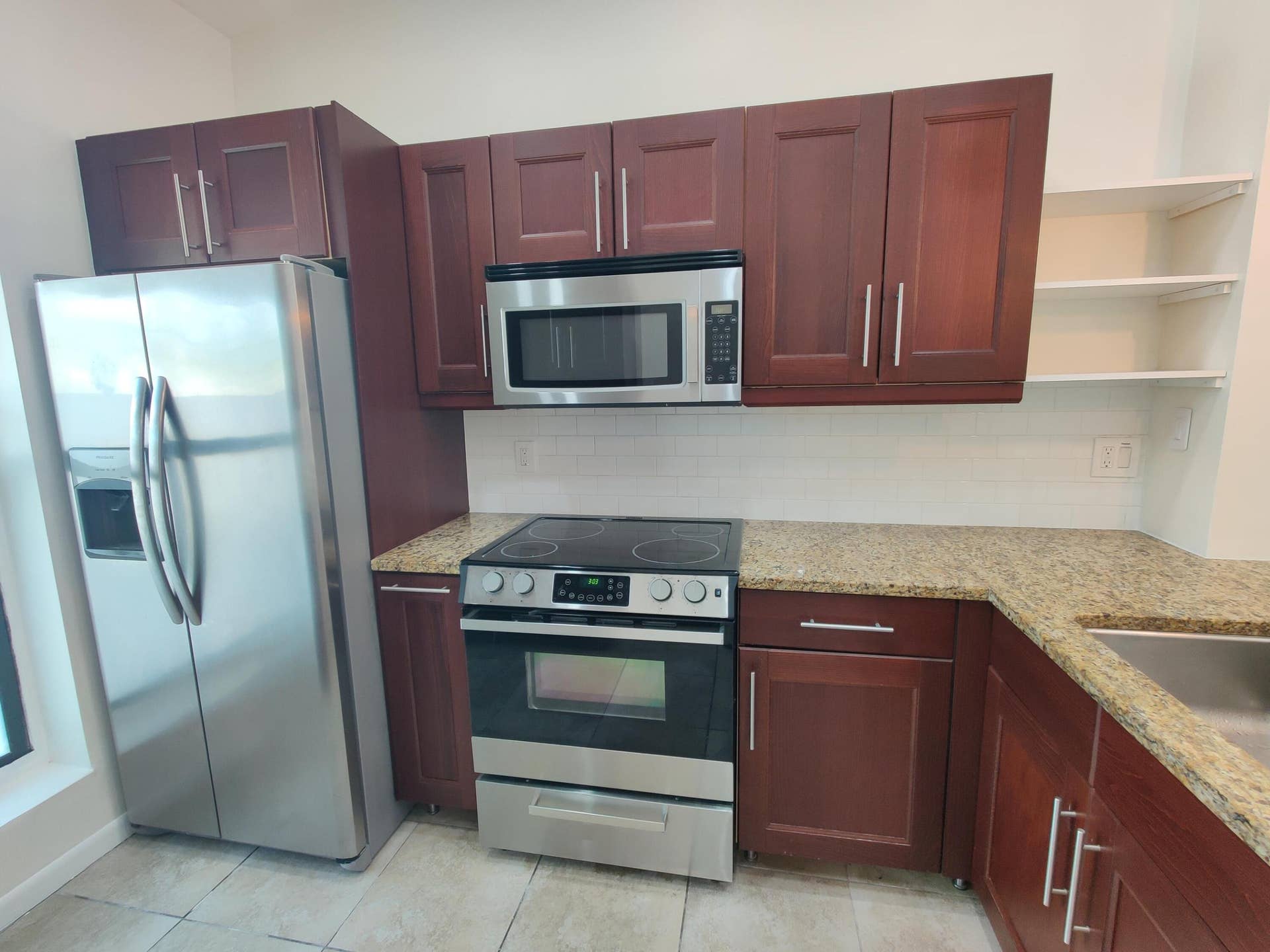 2700 S OAKLAND FOREST Drive, #603, Oakland Park, FL 33309 Kitchen featuring wood-finish cabinetry, stone-surface countertops, stainless steel appliances, and built-in shelving