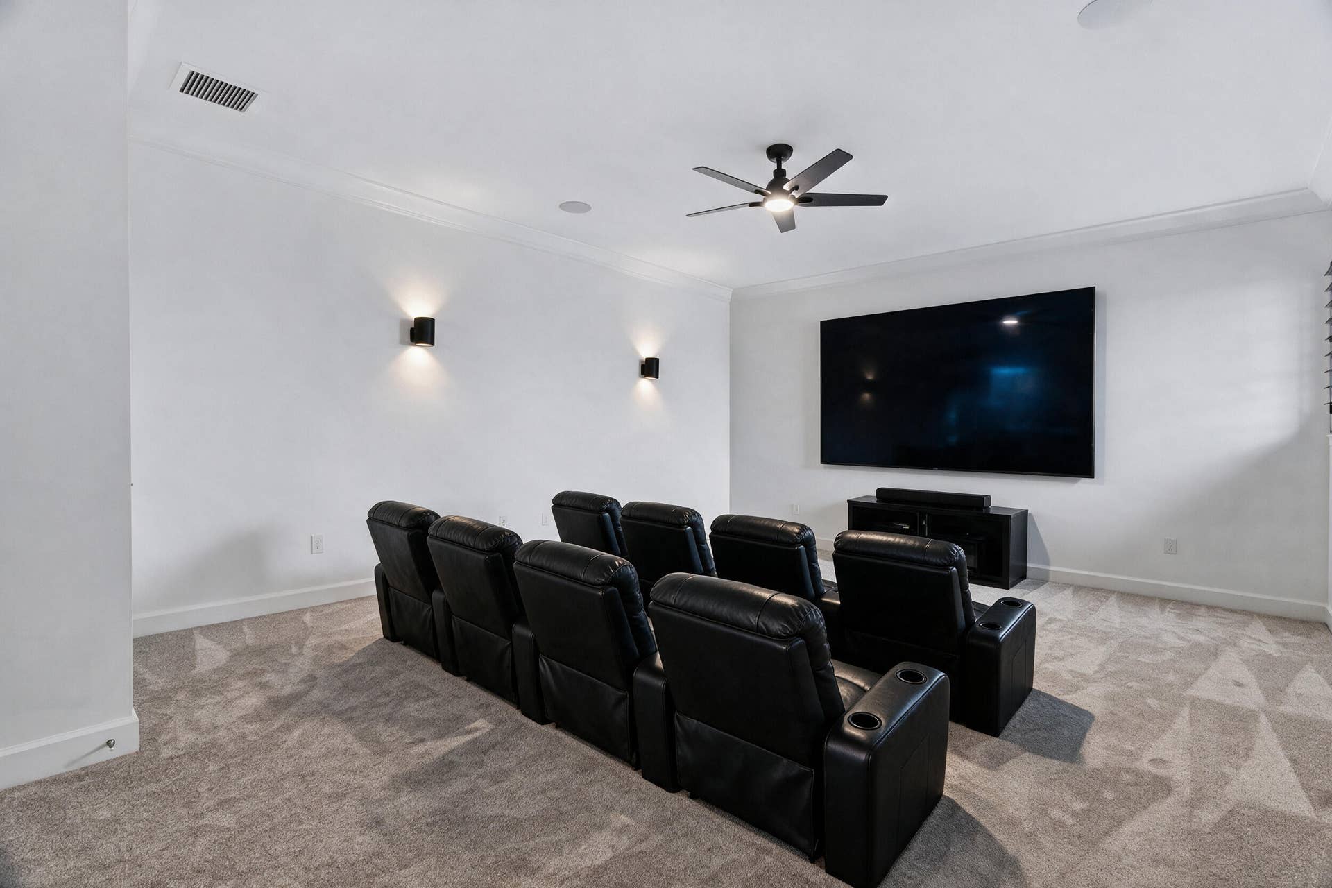 20036 SE BRIDGEWATER Drive, Jupiter, FL 33458 Media room featuring neutral carpeting, a ceiling-mounted fan, dual wall-mounted sconces, and recessed ceiling lighting