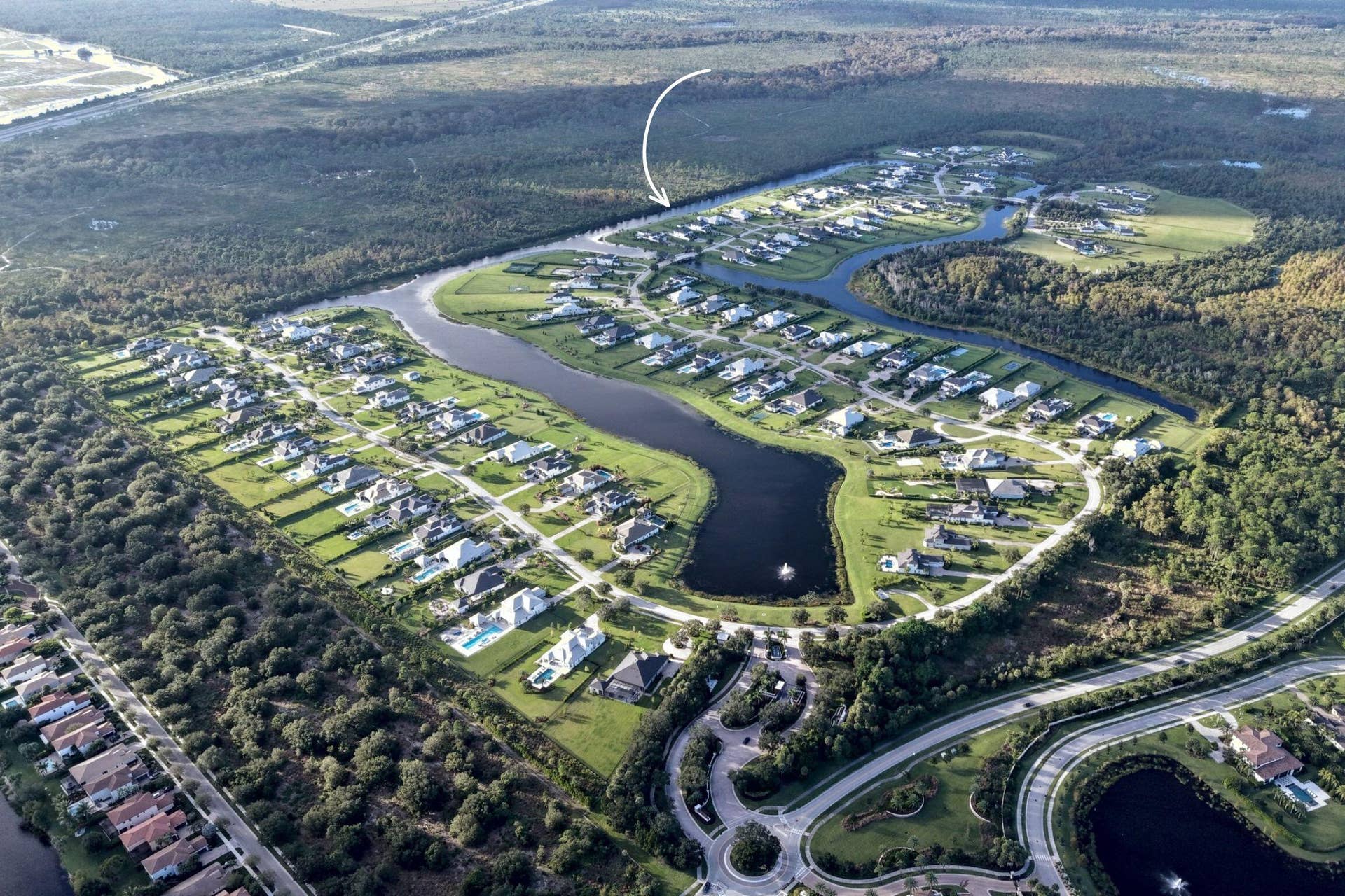 20036 SE BRIDGEWATER Drive, Jupiter, FL 33458 Aerial perspective of a residential development featuring expansive waterways, mature tree lines, and manicured green spaces
