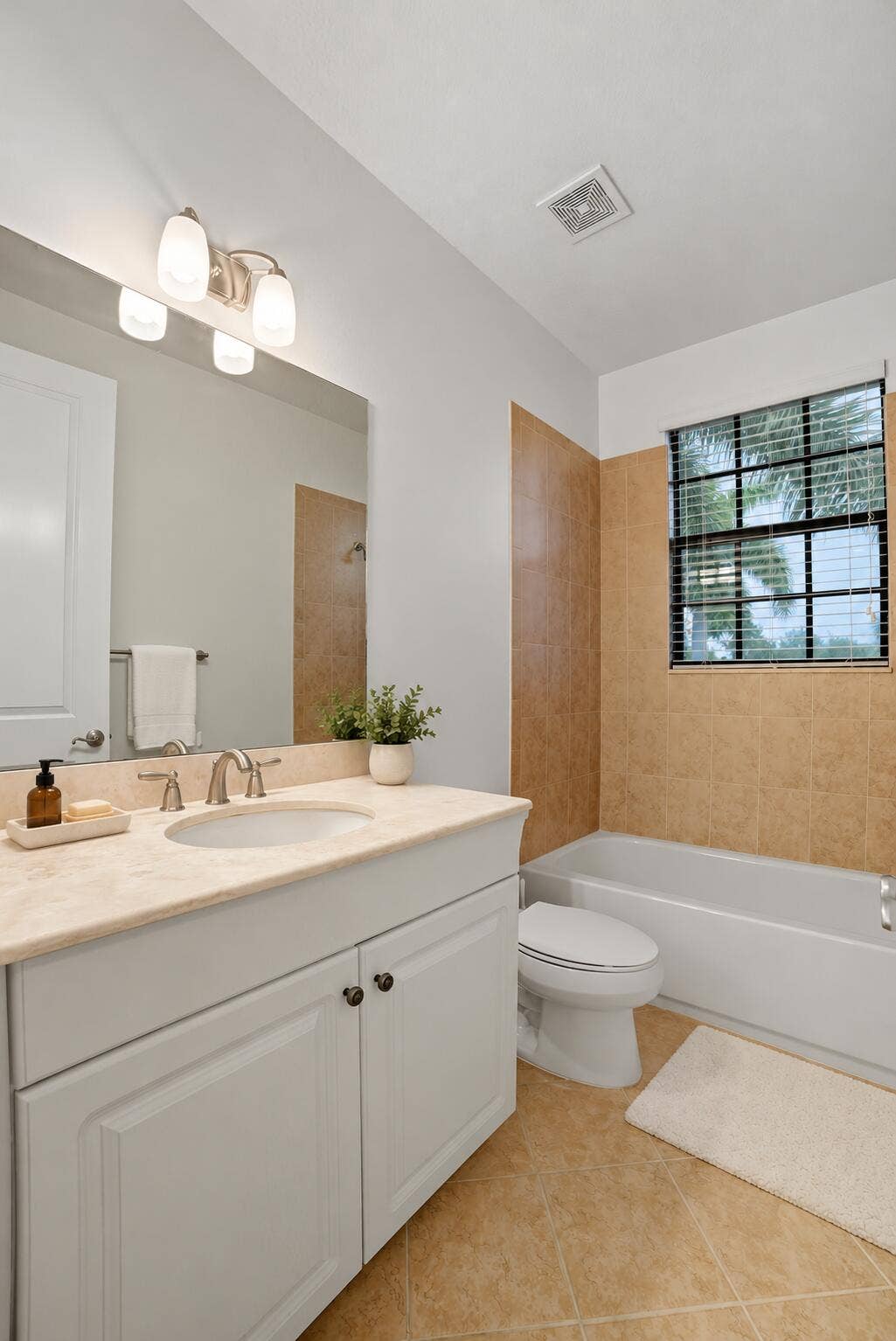 13011 Riverwalk Circle N, Plantation, Plantation, FL 33325 White cabinetry with a stone-top vanity, undermount sink, three-light polished chrome fixture, and tiled tub surround