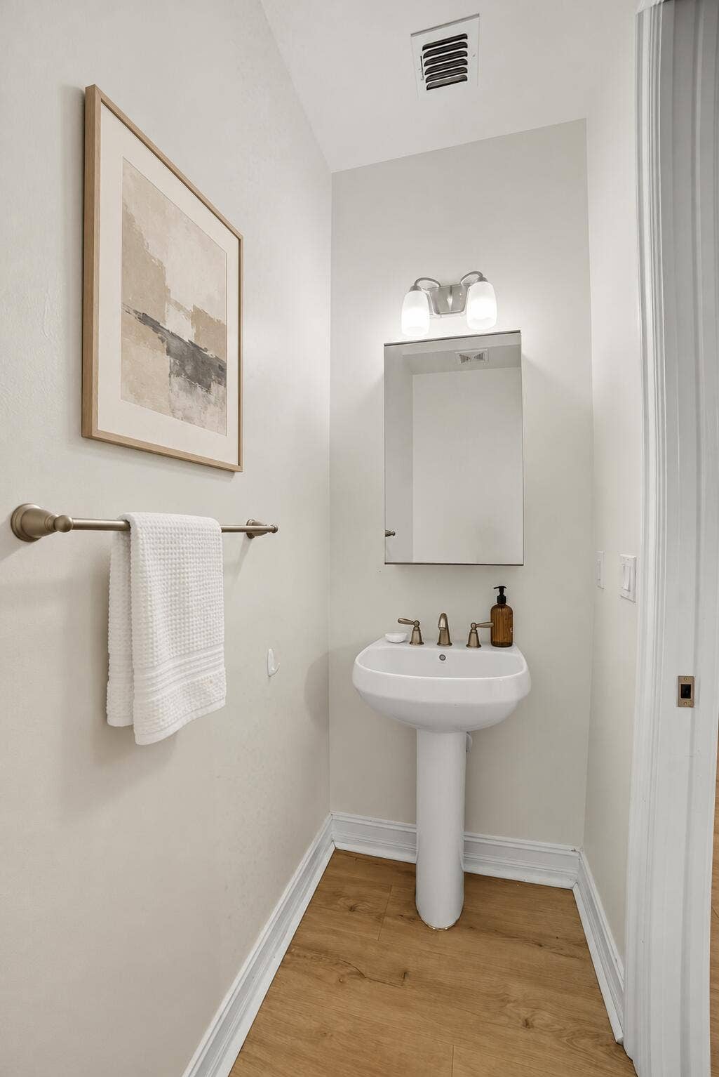 13011 Riverwalk Circle N, Plantation, Plantation, FL 33325 White pedestal sink with a metallic widespread faucet, recessed medicine cabinet, dual-globe wall-mounted light fixture, and wood-finish flooring