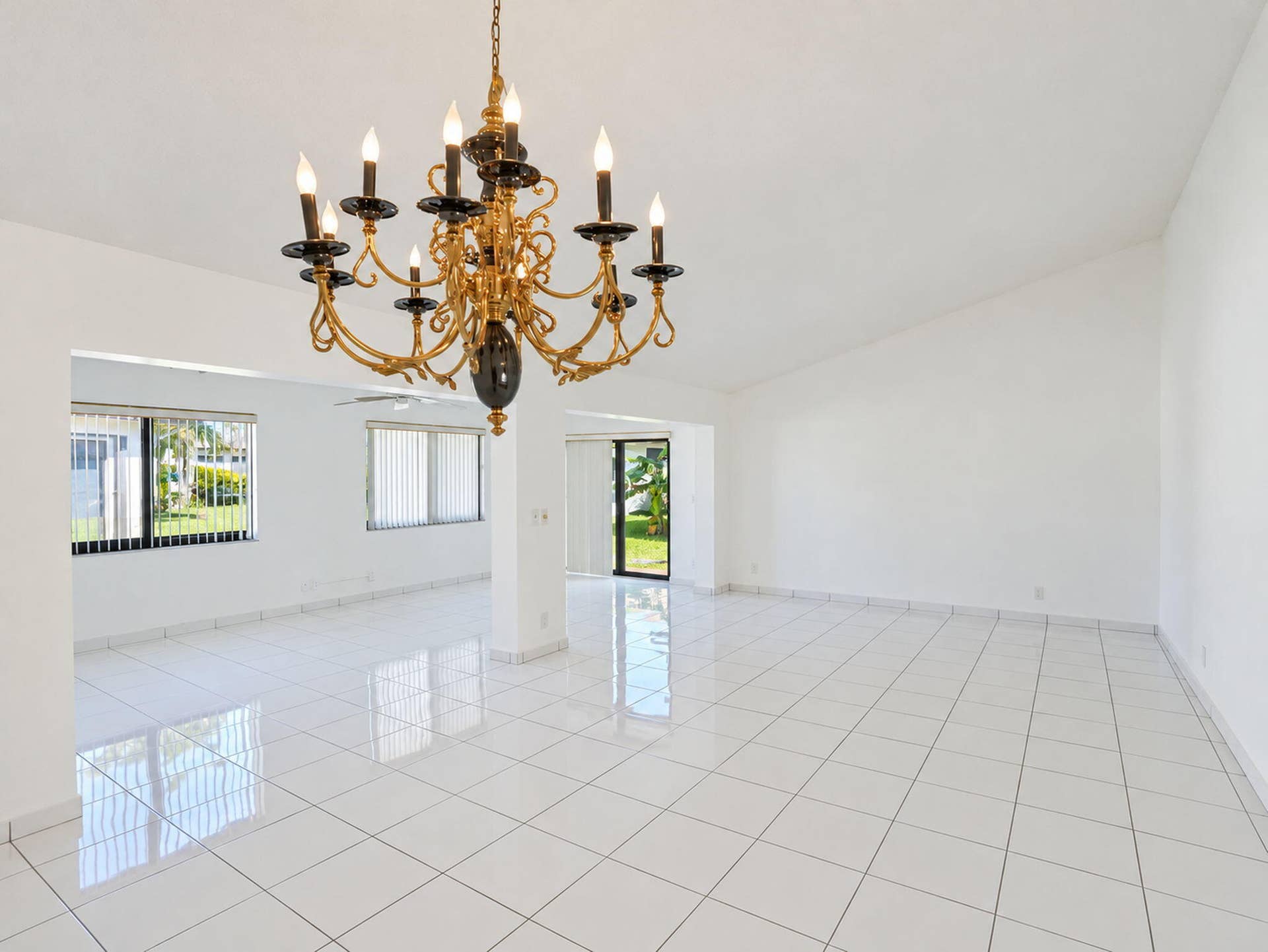 2079 SW 16TH Circle, Deerfield Beach, FL 33442 Spacious interior featuring white tile flooring, vaulted ceilings, and a decorative multi-arm chandelier