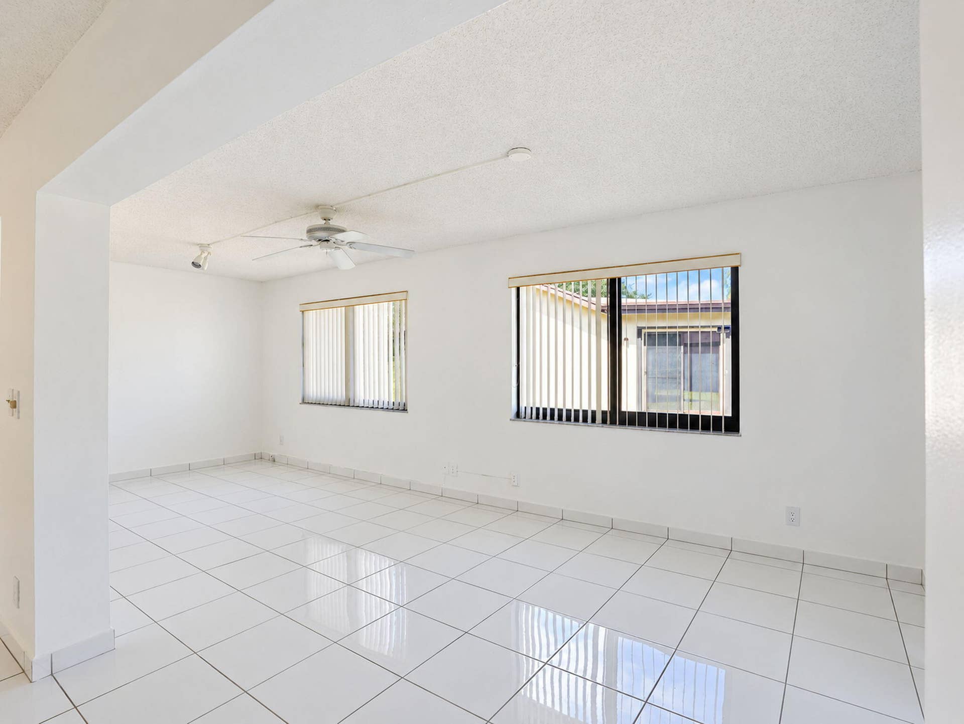 2079 SW 16TH Circle, Deerfield Beach, FL 33442 White tile flooring, dual windows with vertical blinds, and ceiling-mounted track lighting and fan