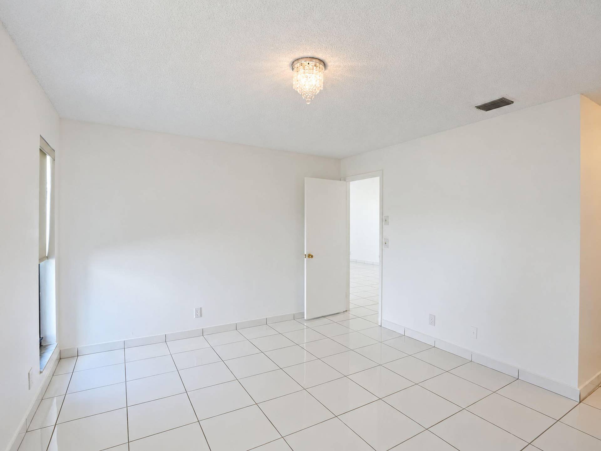 2079 SW 16TH Circle, Deerfield Beach, FL 33442 Interior space featuring polished white tile flooring, neutral wall finishes, and a decorative crystal flush-mount light fixture