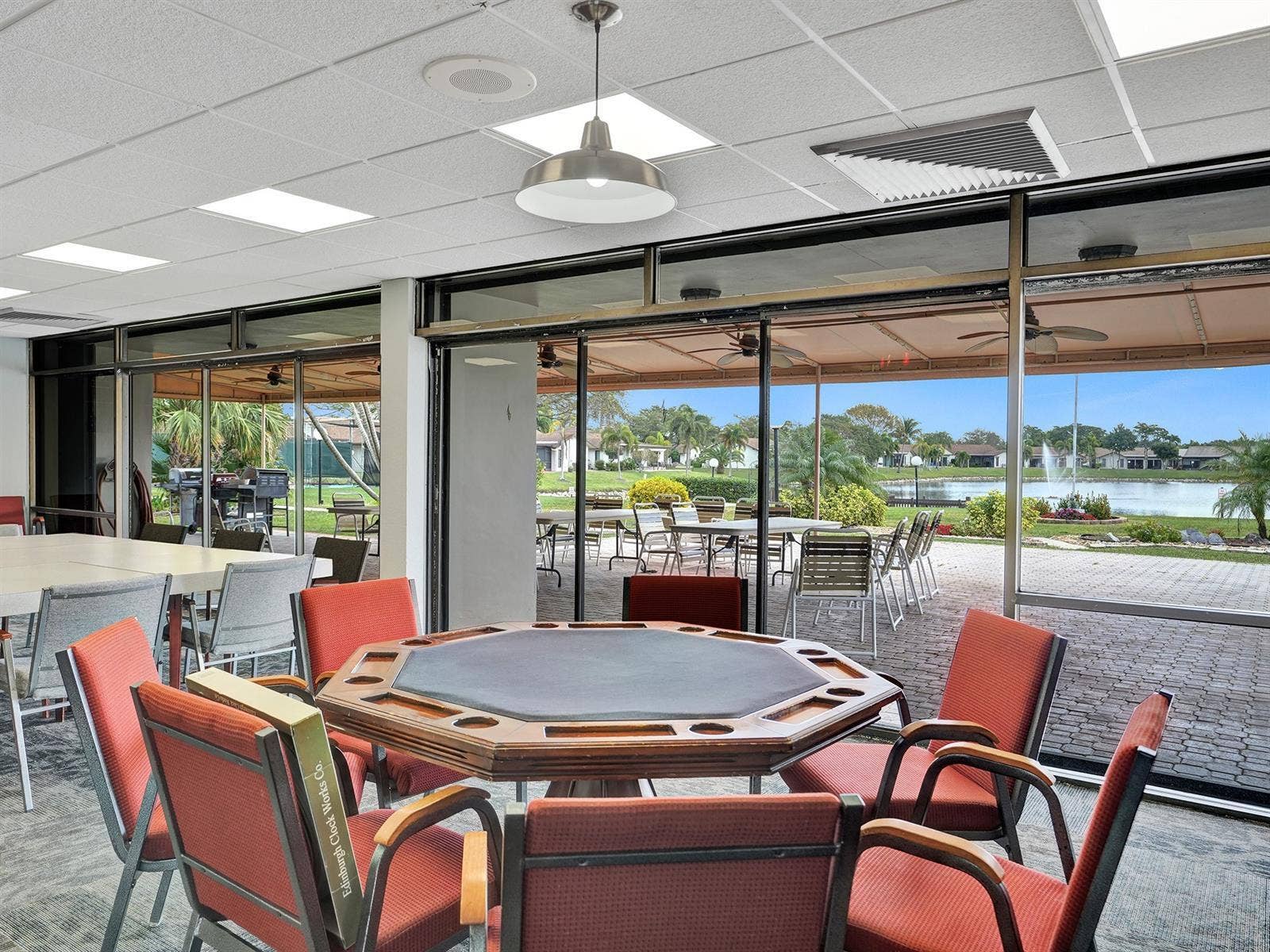 2079 SW 16TH Circle, Deerfield Beach, FL 33442 Expansive floor-to-ceiling glass wall panels with metal framing, drop ceiling with recessed lighting, pendant lighting fixture, and exterior paver patio