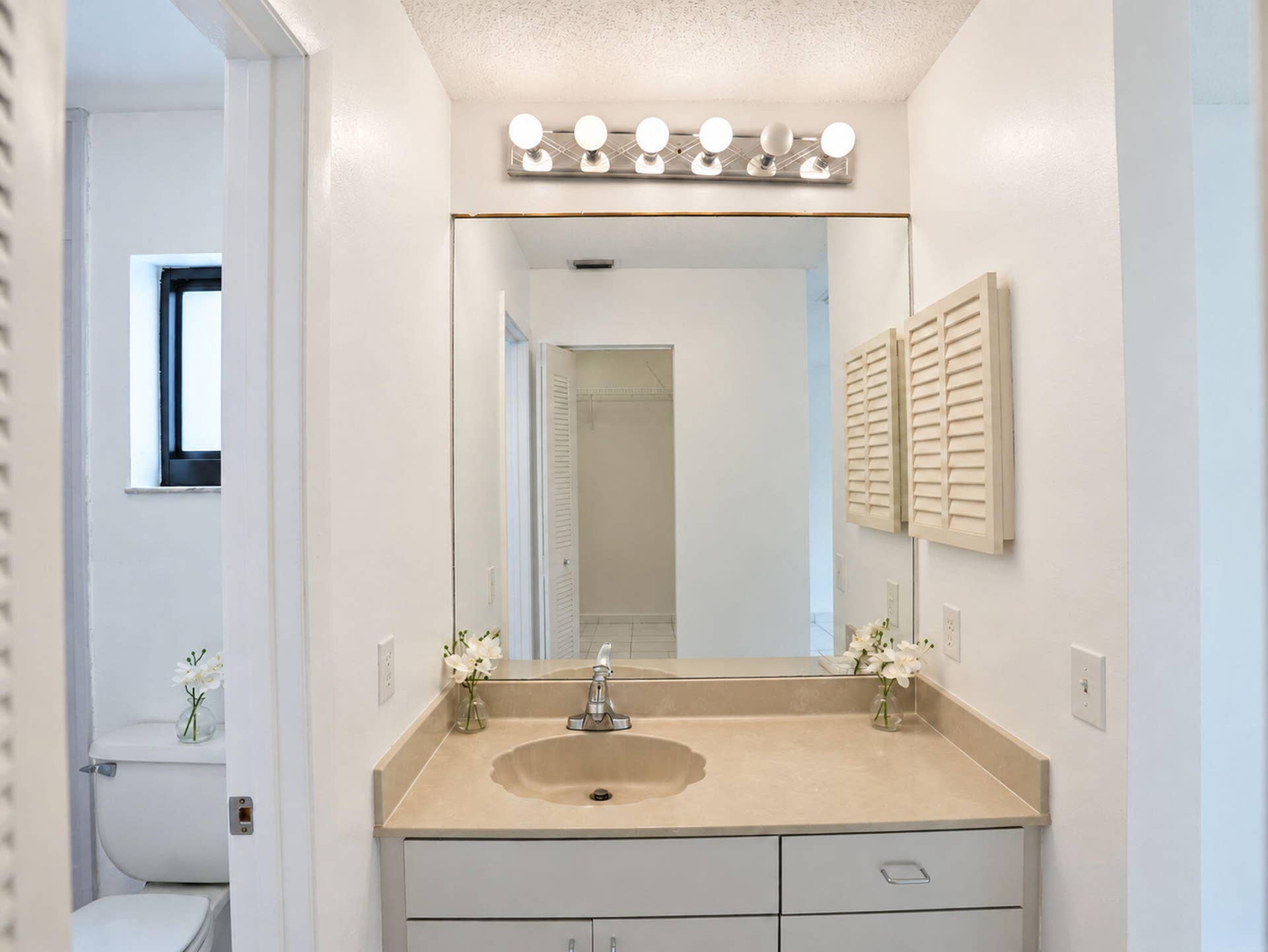 2079 SW 16TH Circle, Deerfield Beach, FL 33442 Bathroom vanity featuring a solid-surface countertop with an integrated scalloped basin, white cabinetry, a large frameless mirror, and a multi-bulb vanity light fixture