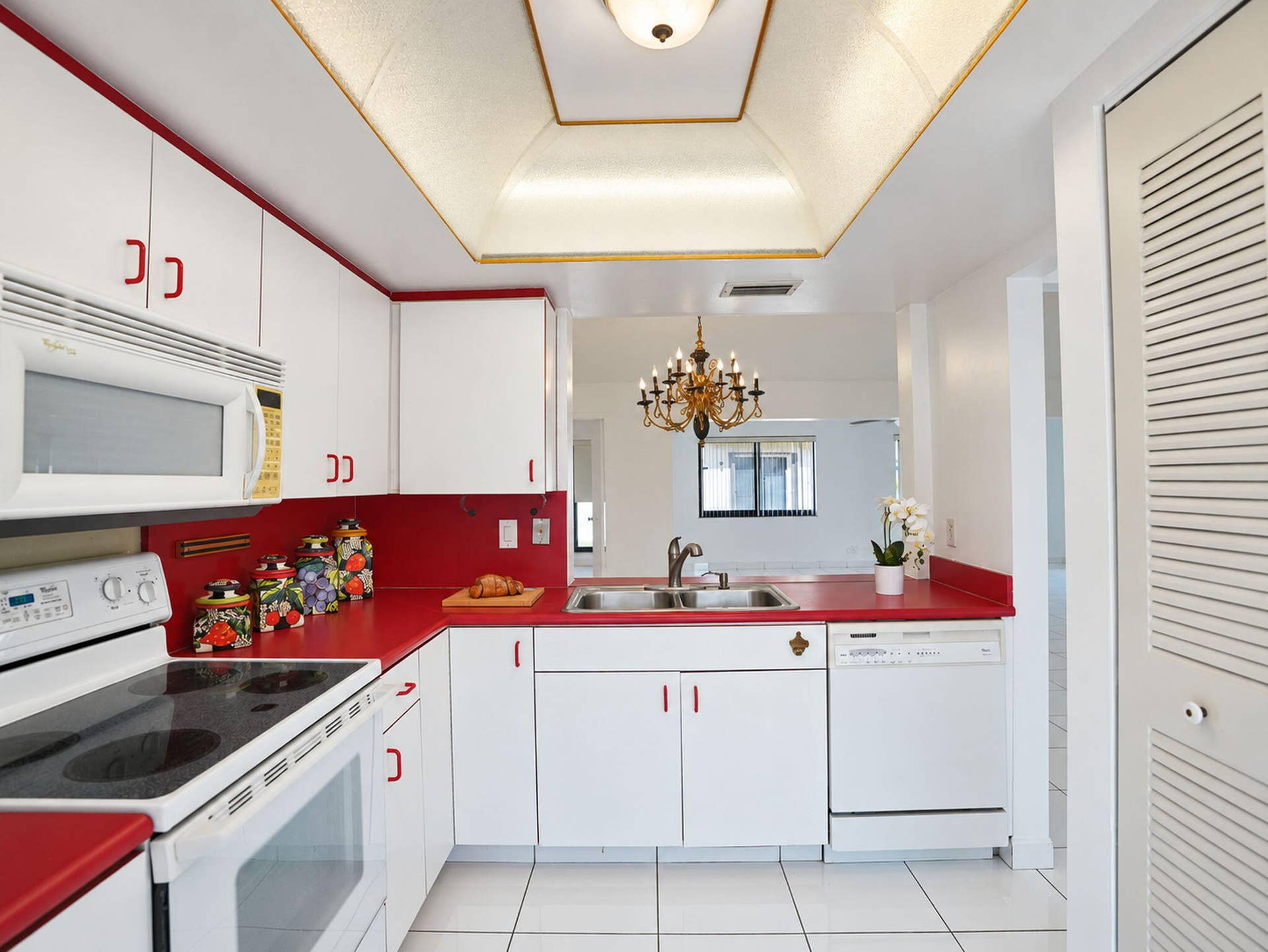 2079 SW 16TH Circle, Deerfield Beach, FL 33442 Kitchen featuring white cabinetry, contrasting solid-surface countertops, tile flooring, built-in microwave, and recessed tray ceiling lighting