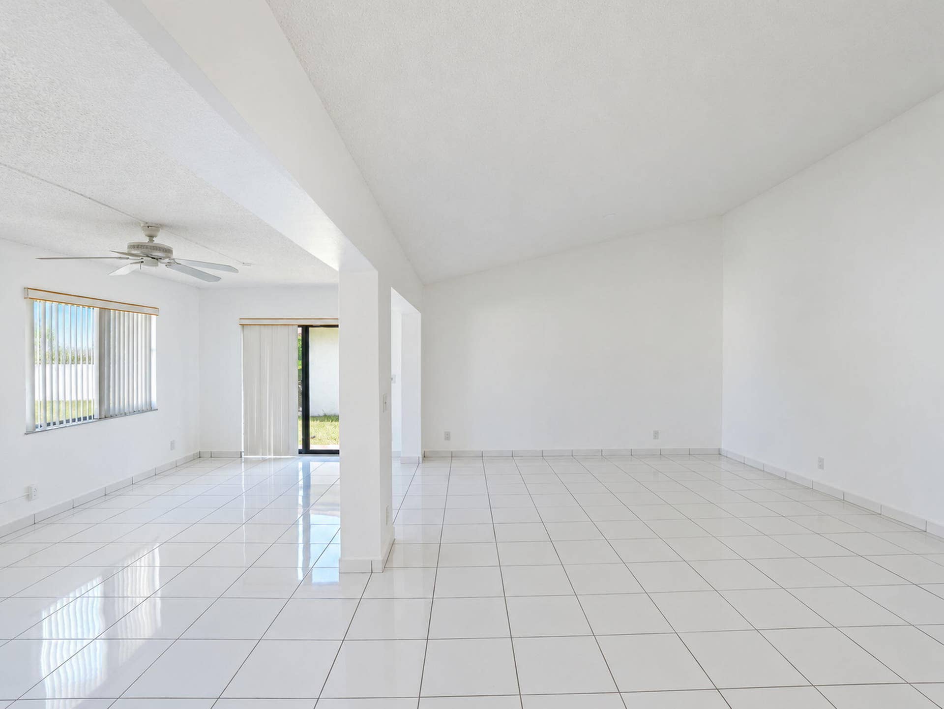 2079 SW 16TH Circle, Deerfield Beach, FL 33442 Open-concept interior featuring vaulted ceilings, polished tile flooring, a mounted ceiling fan, and sliding glass doors