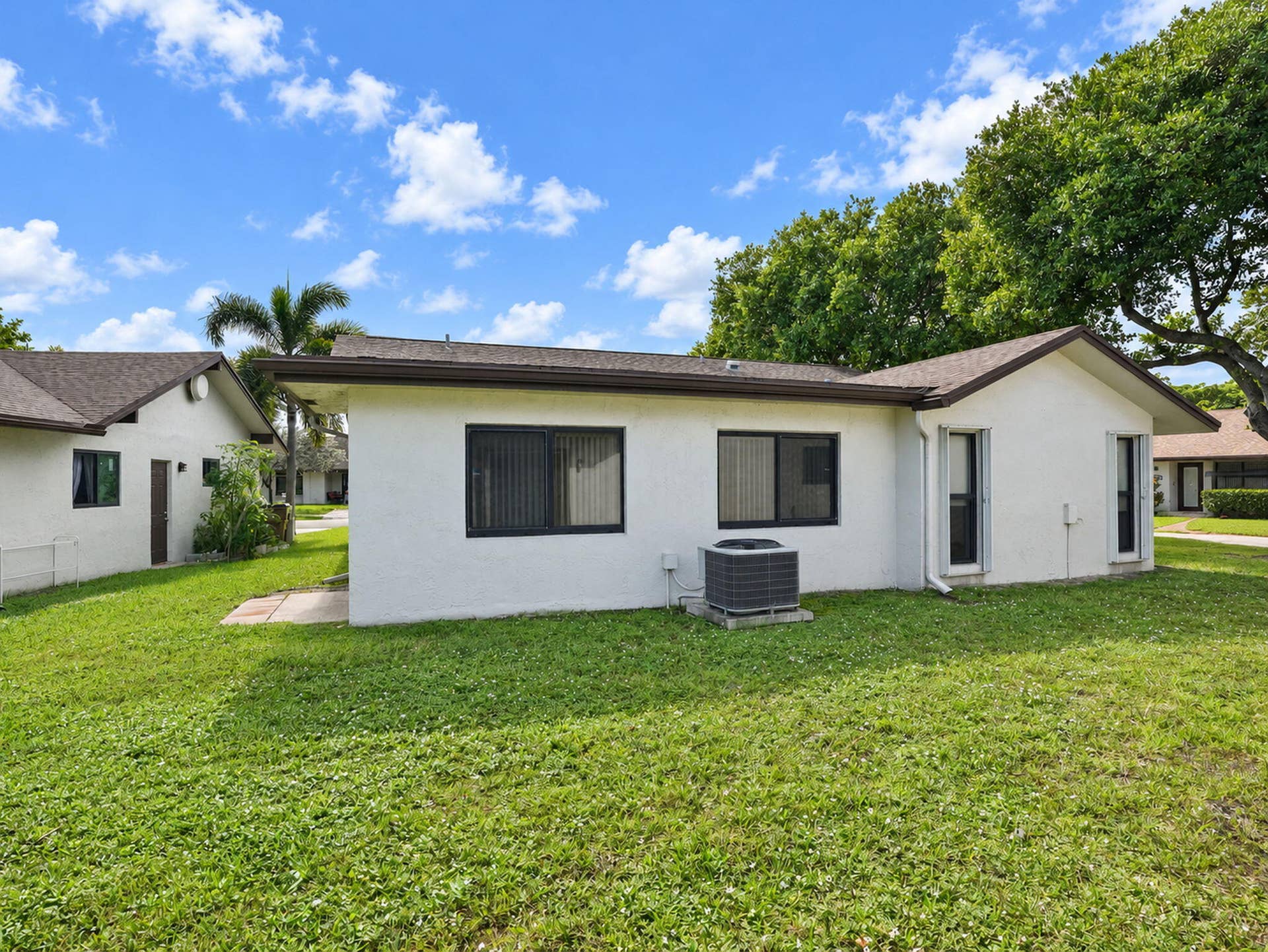 2079 SW 16TH Circle, Deerfield Beach, FL 33442 Stucco exterior with a low-pitch hip roof, dark-trimmed window frames, and expansive lawn area