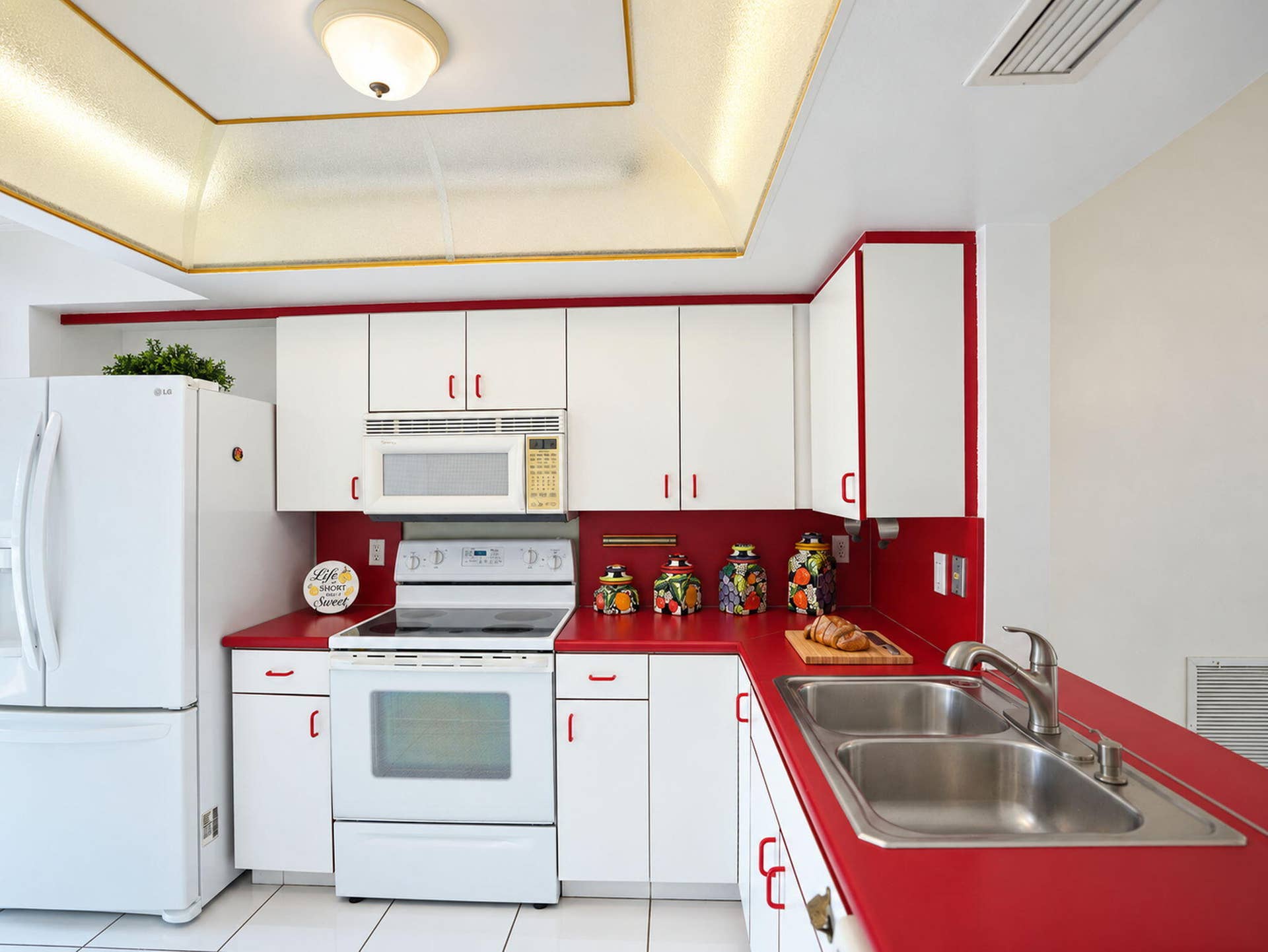 2079 SW 16TH Circle, Deerfield Beach, FL 33442 Kitchen featuring white cabinetry, solid-surface countertops, dual-basin stainless steel sink with pull-down faucet, recessed tray ceiling, and tile flooring