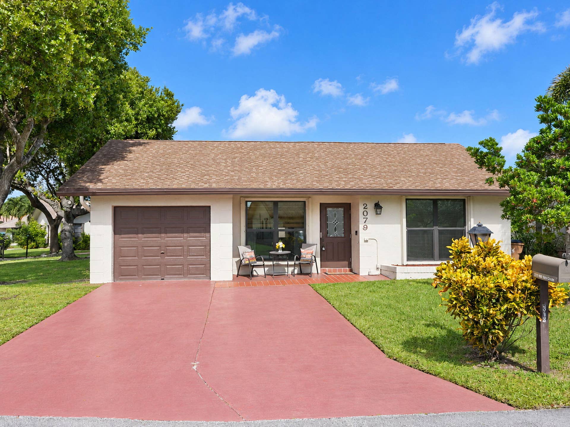 2079 SW 16TH Circle, Deerfield Beach, FL 33442 Single-story exterior featuring a shingled roof, stucco siding, an attached one-car garage, and a paved driveway