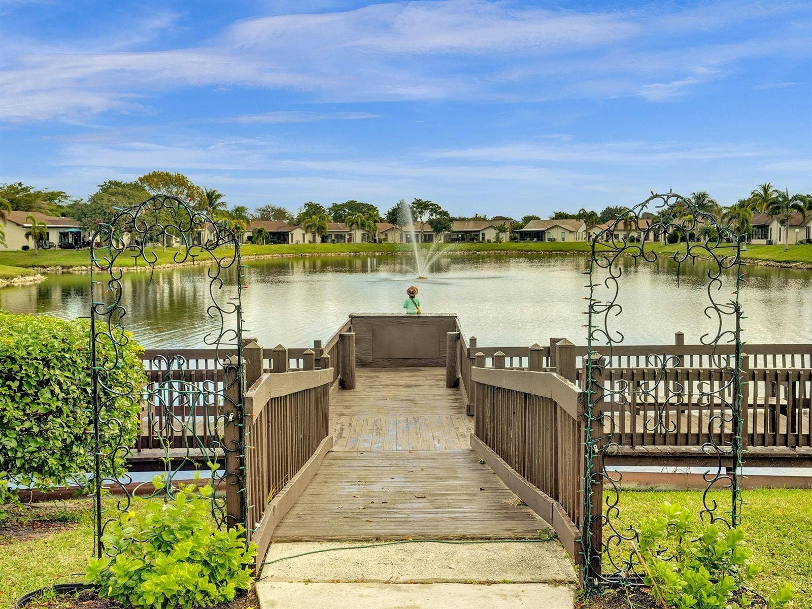 2079 SW 16TH Circle, Deerfield Beach, FL 33442 Waterfront wooden pier featuring a decorative metal archway, integrated railings, and a water fountain