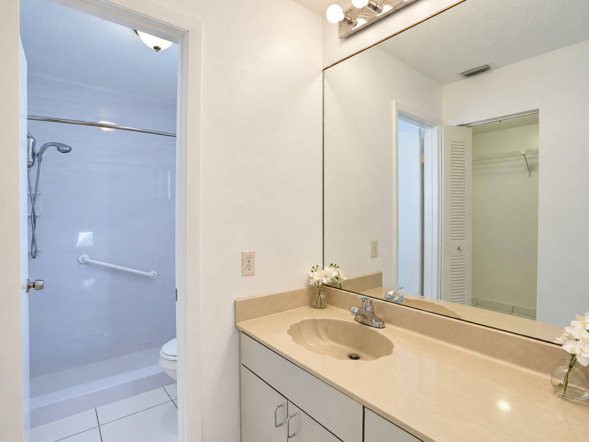 2079 SW 16TH Circle, Deerfield Beach, FL 33442 Bathroom featuring a solid-surface vanity countertop with an integrated scalloped sink, large-format wall mirror, chrome plumbing fixtures, and white cabinetry