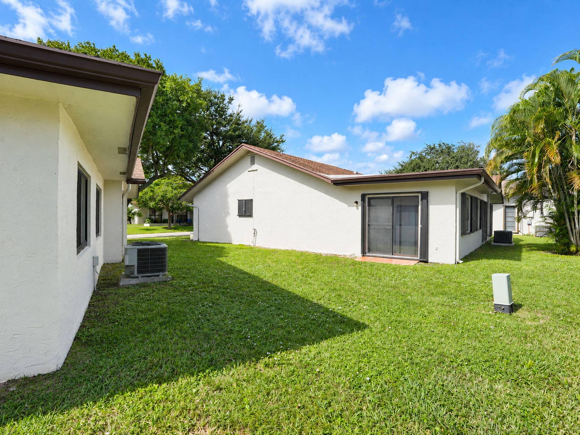 2079 SW 16TH Circle, Deerfield Beach, FL 33442 Stucco exterior with sliding glass doors, shingle roofing, and expansive lawn area