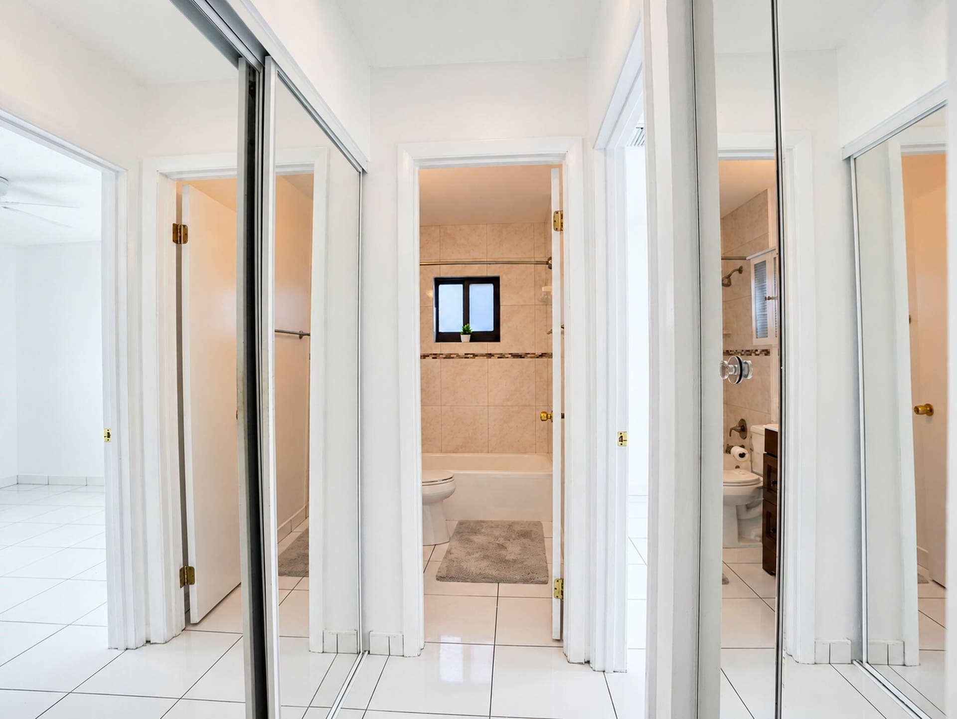 2079 SW 16TH Circle, Deerfield Beach, FL 33442 Ceramic tile flooring, sliding mirrored closet doors, and interior doorway with access to a bathroom featuring stone-finish wall tile and a built-in bathtub