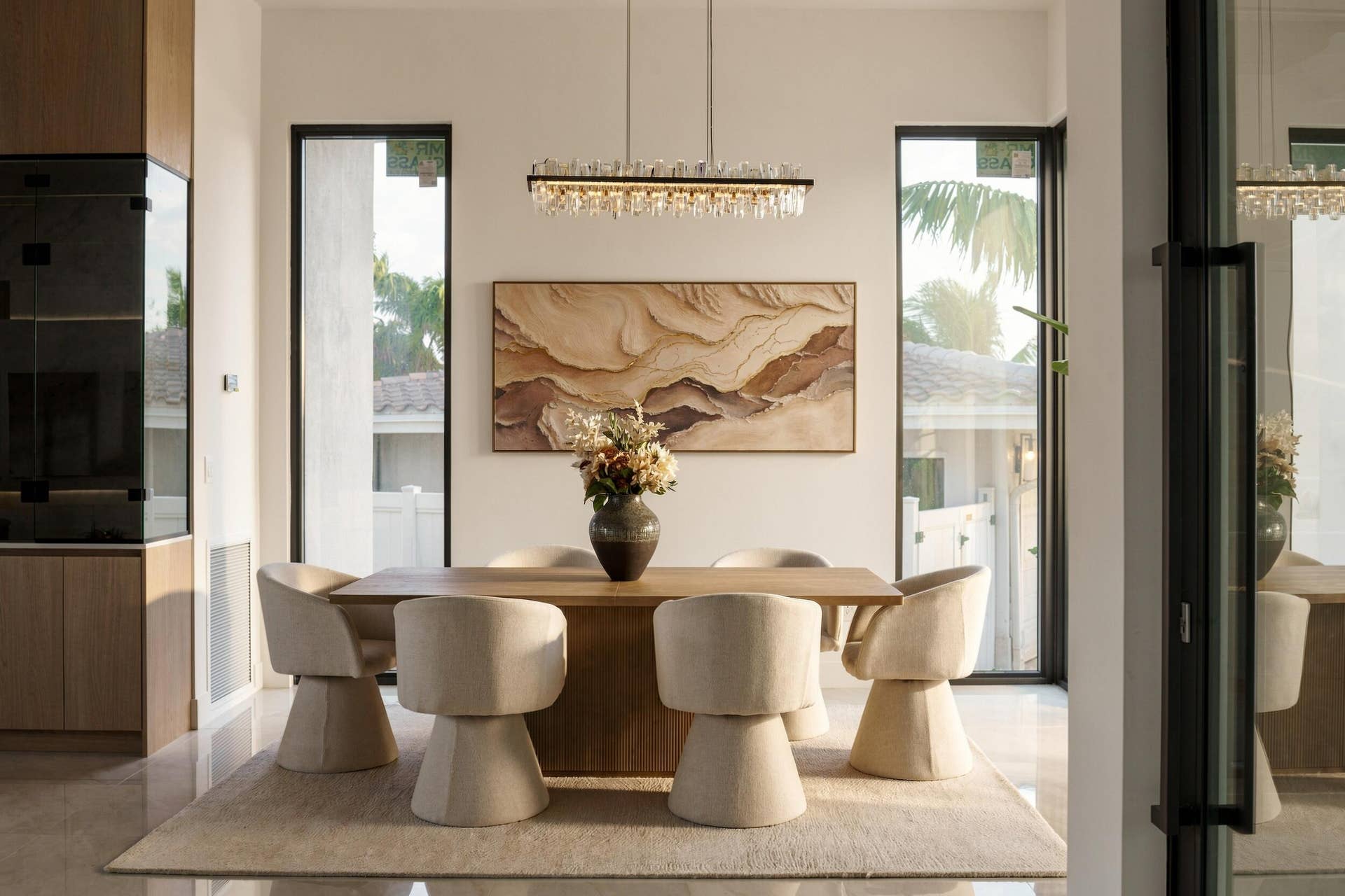 4931 NE 25TH Avenue, Lighthouse Point, FL 33064 Dining area featuring floor-to-ceiling windows, custom built-in cabinetry, polished stone flooring, and a linear crystal chandelier