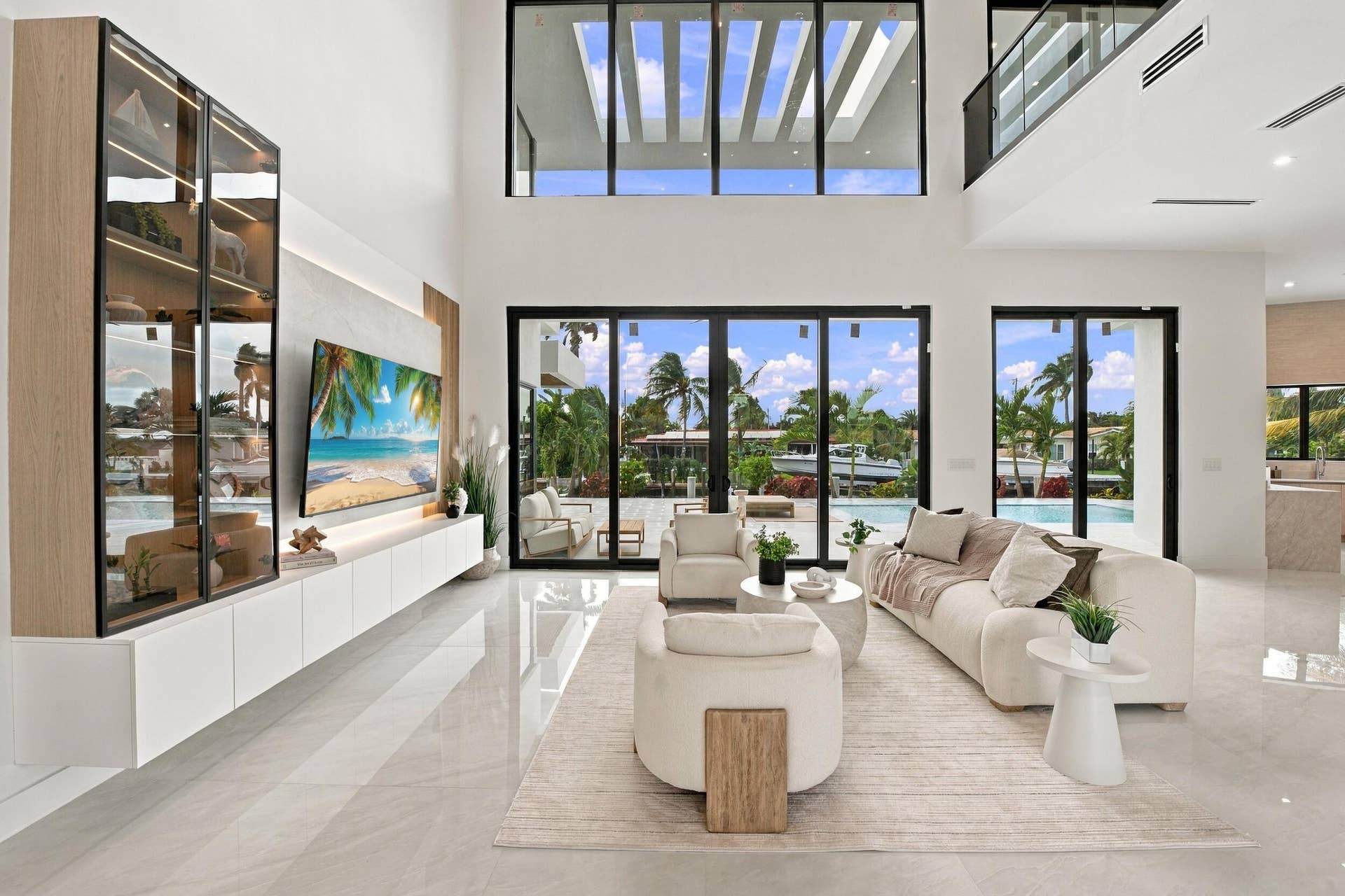 4931 NE 25TH Avenue, Lighthouse Point, FL 33064 Double-height ceilings, floor-to-ceiling glass panel walls, custom built-in wood-trim cabinetry, stone-finish flooring, and recessed architectural lighting