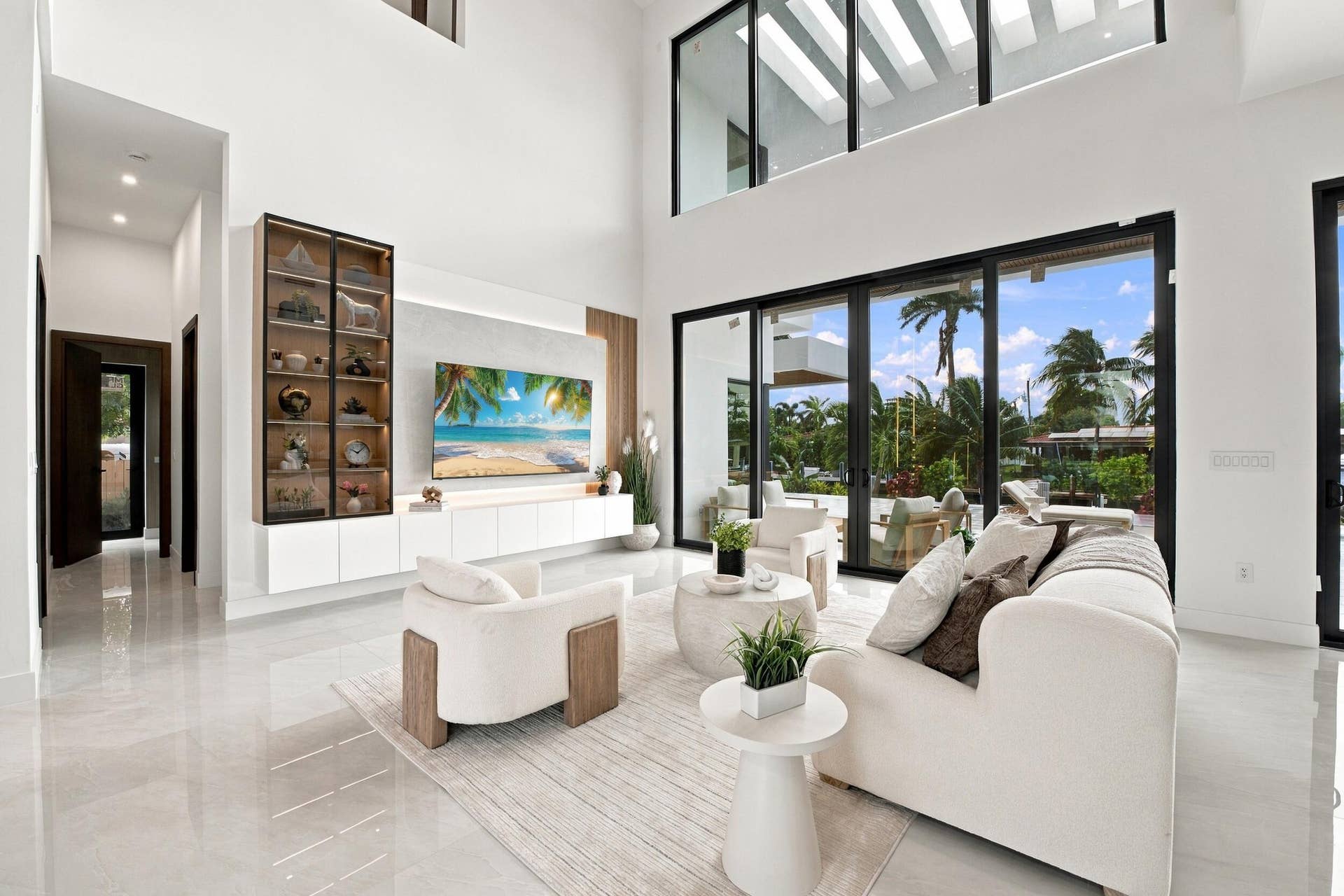 4931 NE 25TH Avenue, Lighthouse Point, FL 33064 Double-height ceilings, floor-to-ceiling glass wall, built-in floor-to-ceiling cabinetry with integrated display lighting, and polished stone-finish flooring
