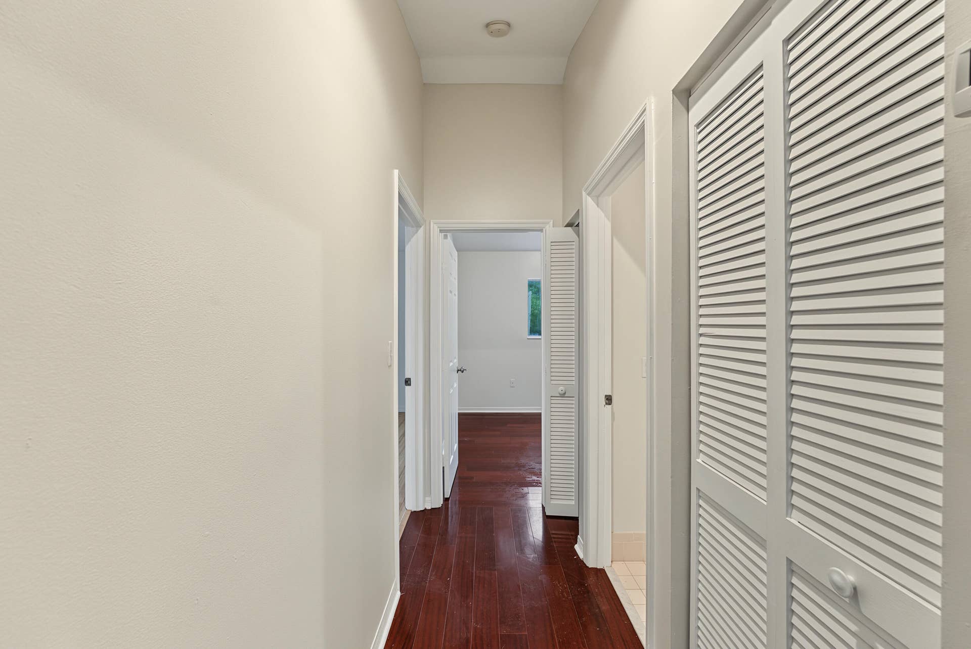 21109 NE 3RD Court, Miami, FL 33179 Hallway featuring high ceilings, wood-finish flooring, and white louvered closet doors