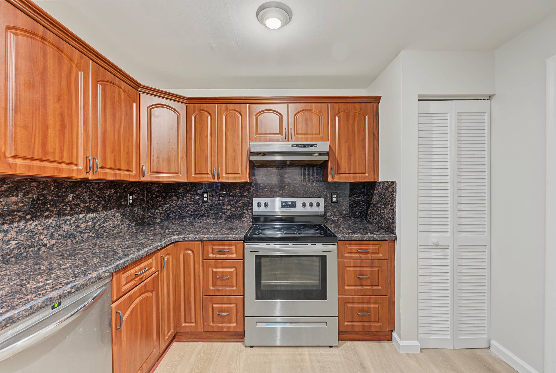21109 NE 3RD Court, Miami, FL 33179 Kitchen featuring wood cabinetry, stone-surface countertops, stone backsplash, stainless steel range with overhead hood, and light-tone wood-finish flooring