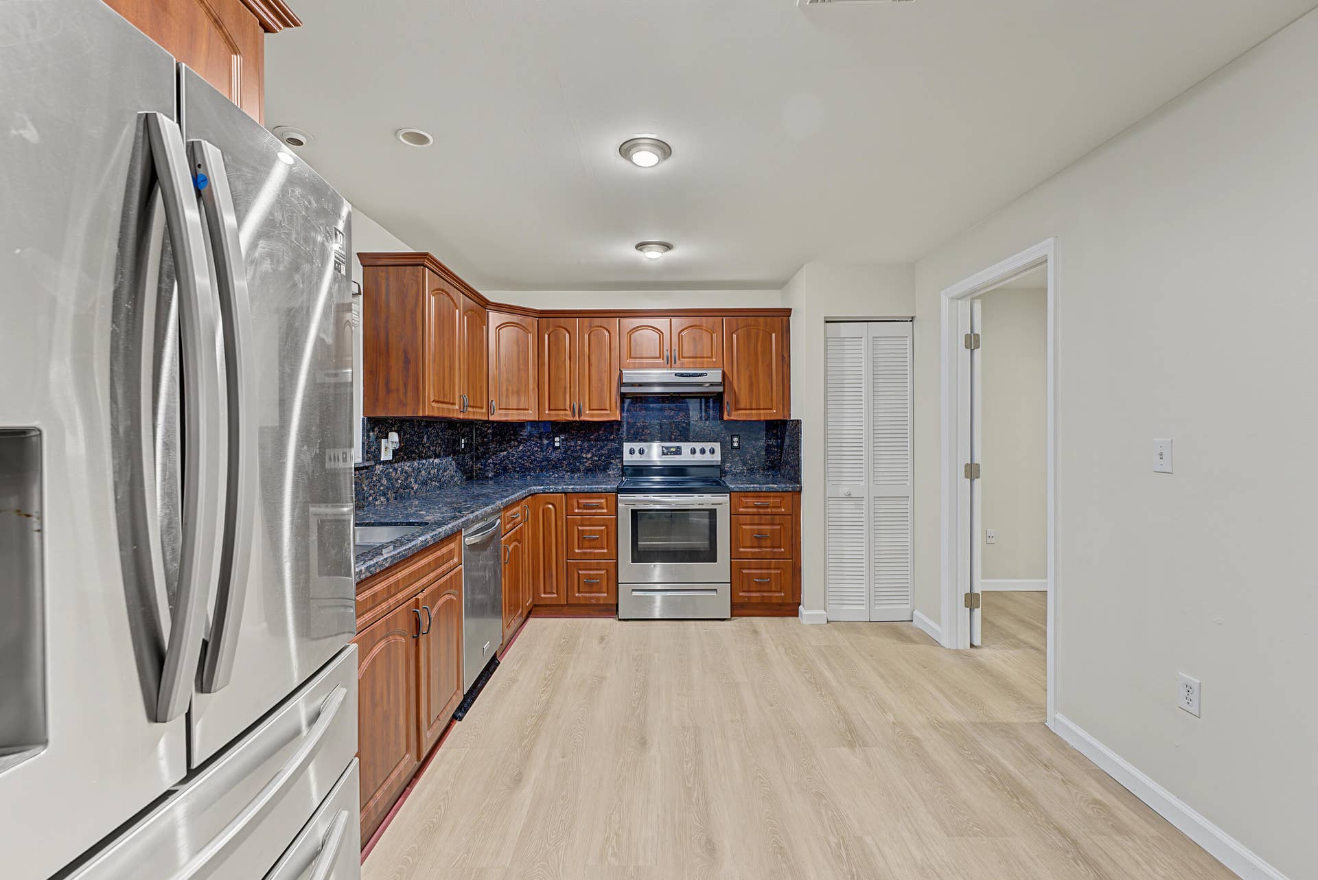 21109 NE 3RD Court, Miami, FL 33179 Kitchen featuring wood cabinetry, stone-surface countertops, stainless steel appliances, and wood-finish flooring