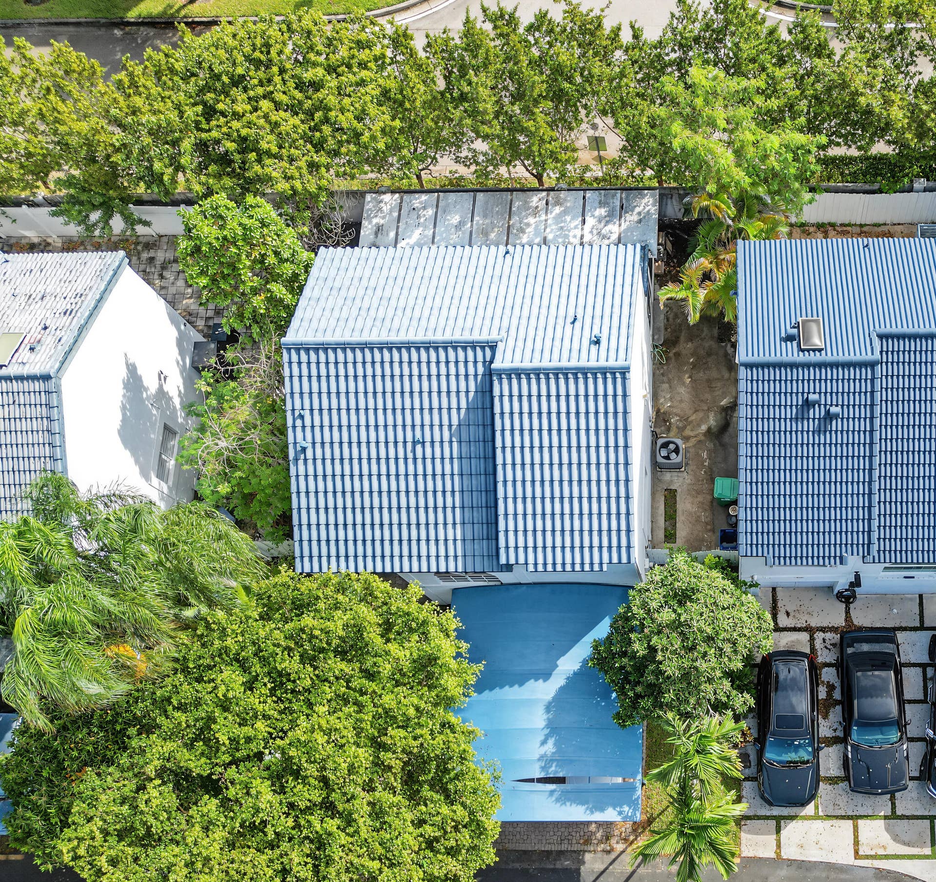 21109 NE 3RD Court, Miami, FL 33179 Aerial view featuring a multi-pitched roof with blue tile roofing, a covered front entryway, and a paved driveway with integrated landscaping grid