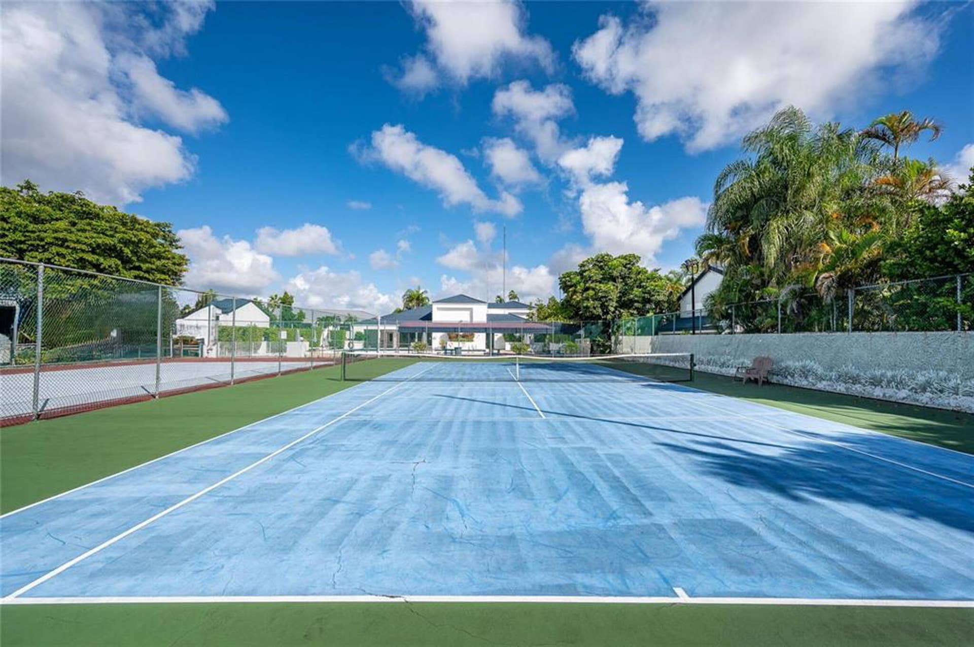 21109 NE 3RD Court, Miami, FL 33179 Dual-court outdoor tennis facility featuring painted hard surfaces, perimeter chain-link fencing, and mature landscaping