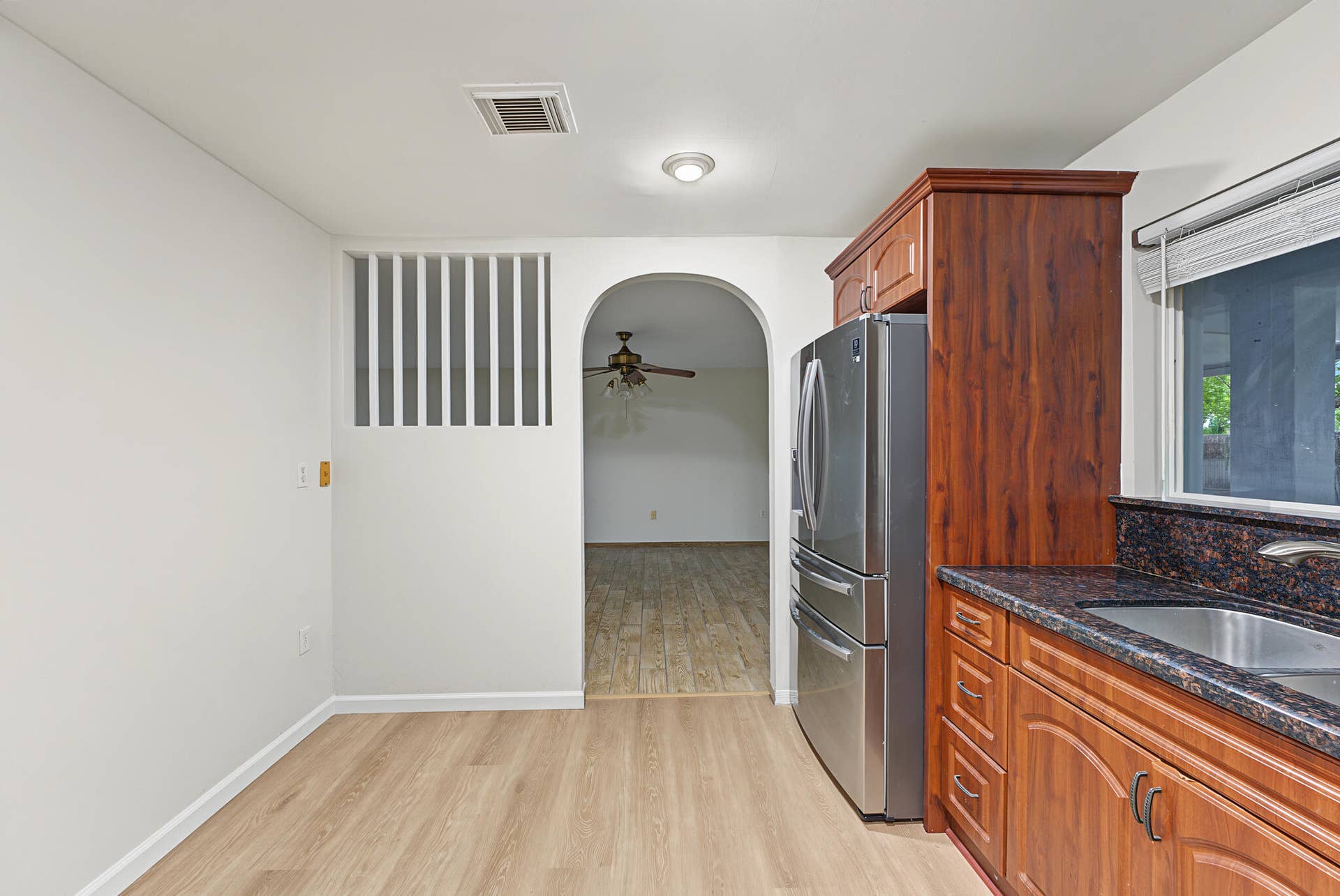 21109 NE 3RD Court, Miami, FL 33179 Kitchen featuring wood-finish cabinetry, stainless steel refrigerator, dark stone-style countertops, wood-finish flooring, and an arched entry