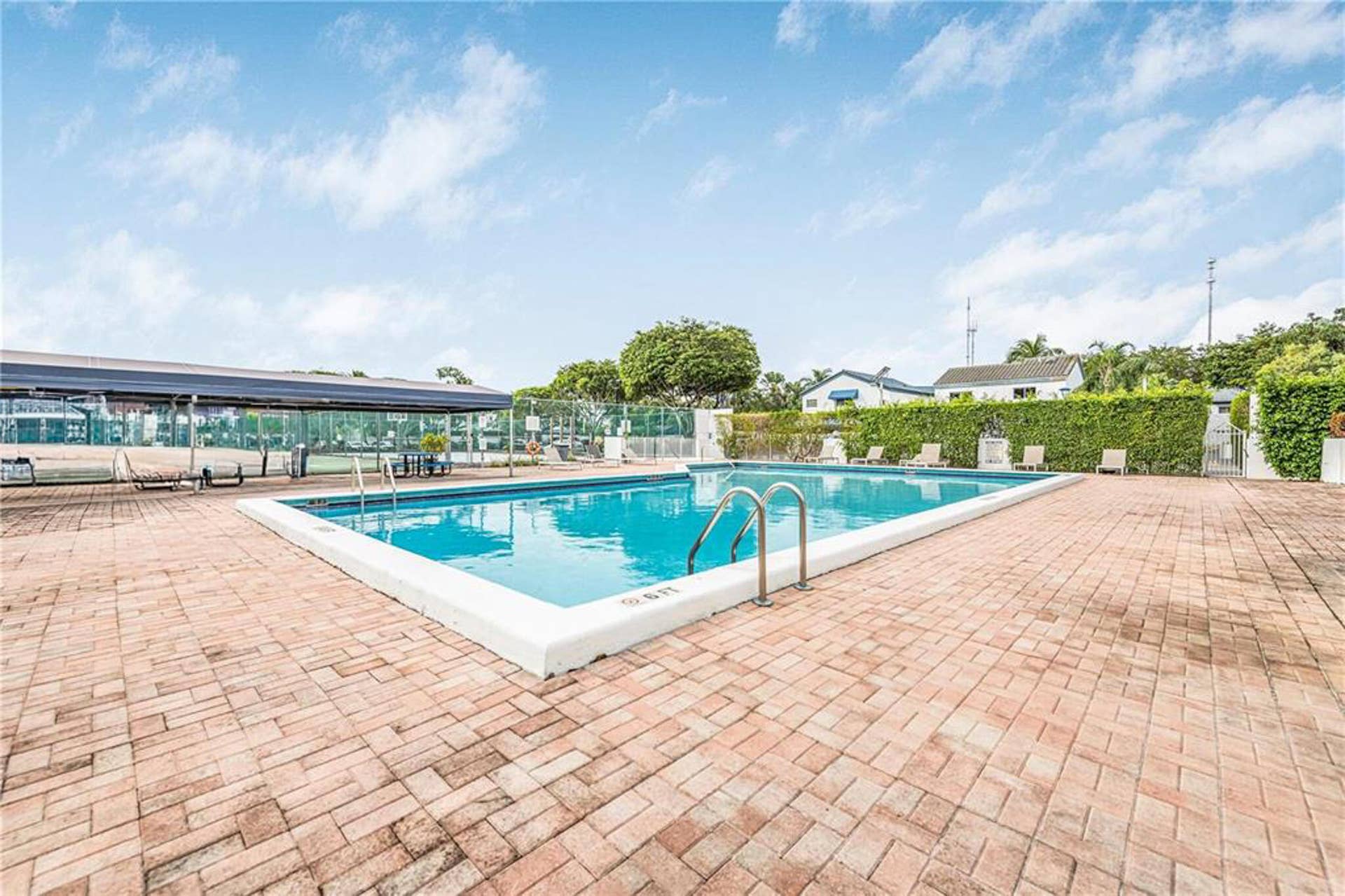 21109 NE 3RD Court, Miami, FL 33179 Outdoor swimming pool featuring a brick-paved deck, perimeter privacy hedging, and an attached covered structure