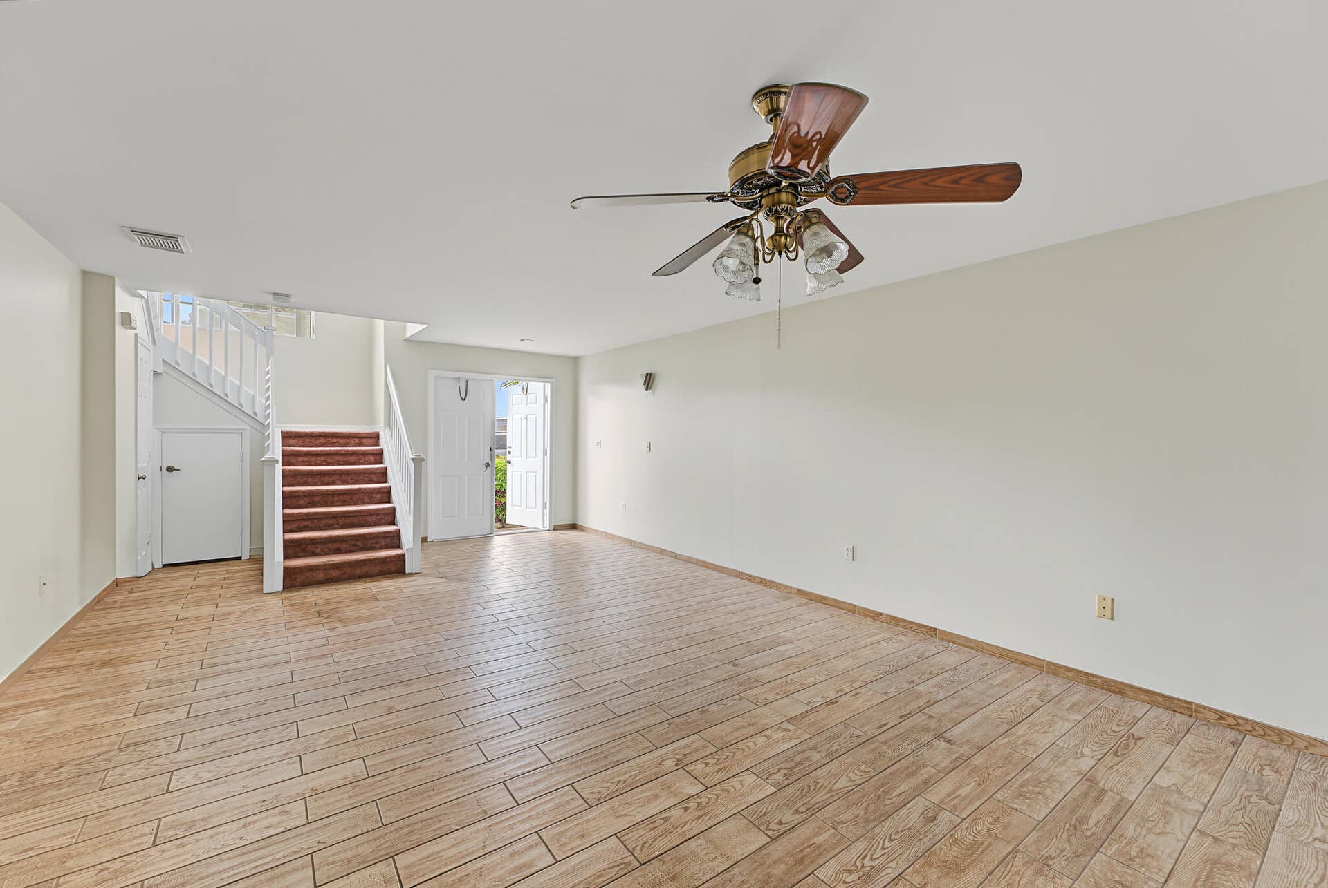 21109 NE 3RD Court, Miami, FL 33179 Open-concept interior featuring wood-finish flooring, a ceiling fan with integrated lighting, and a staircase with white balusters