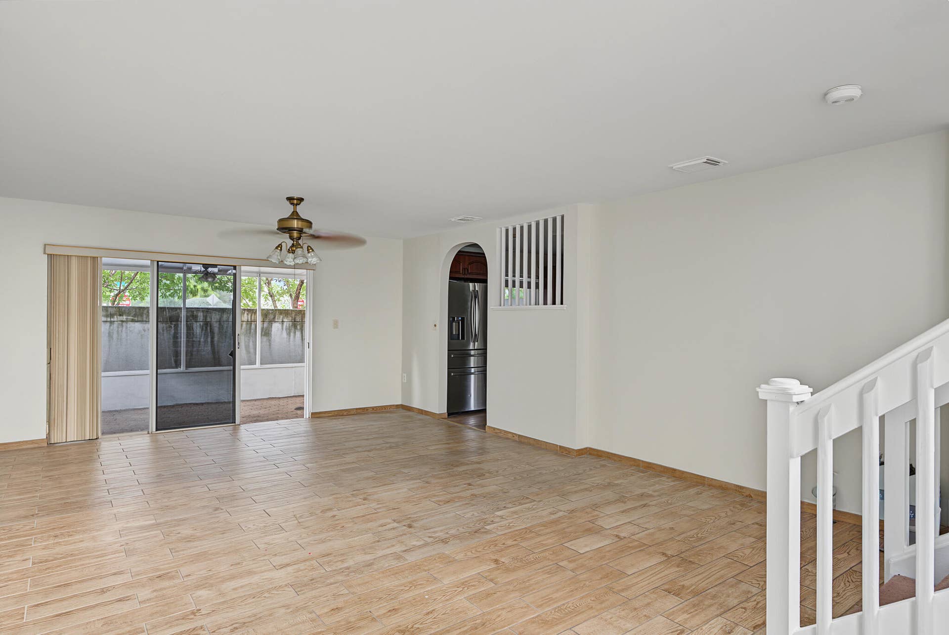 21109 NE 3RD Court, Miami, FL 33179 Open-concept area featuring wood-finish tile flooring, arched doorway with decorative spindles, sliding glass doors, and a ceiling fan with integrated light fixture